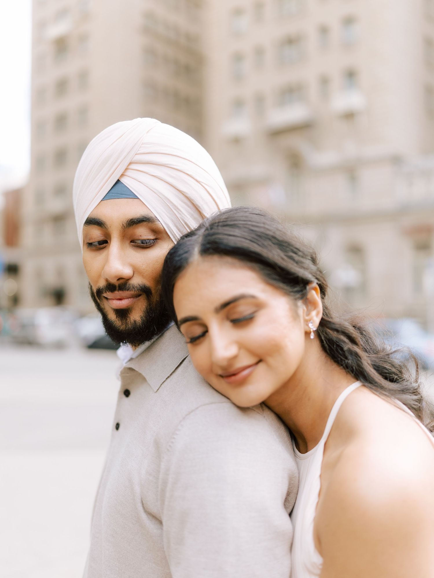 Woman rests her head on mans shoulder in a serene urban engagement portrait.