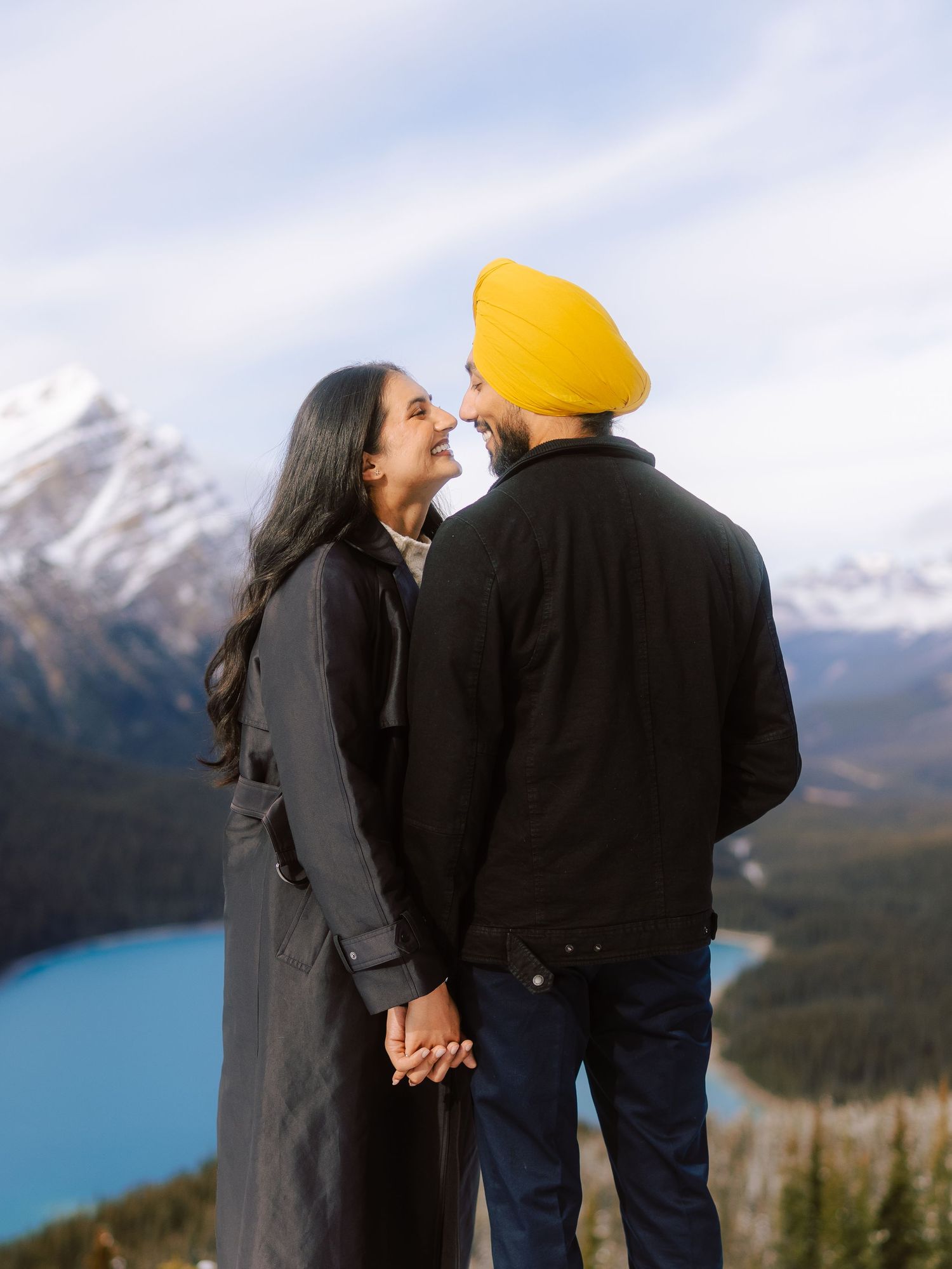 South Asian couple holding hands and sharing a tender moment with Peyto Lake backdrop.