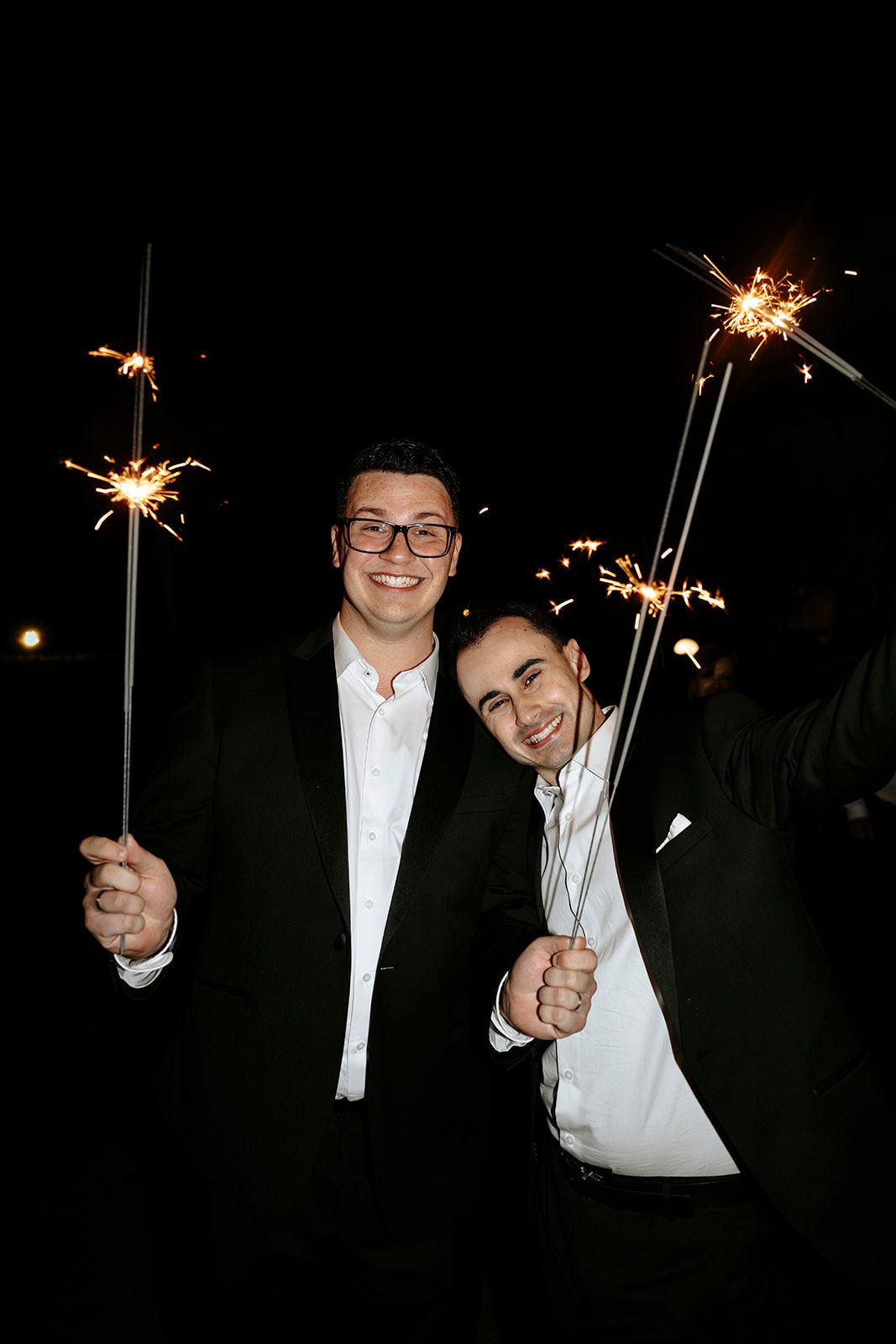 People holding sparklers at night creating festive light trails.