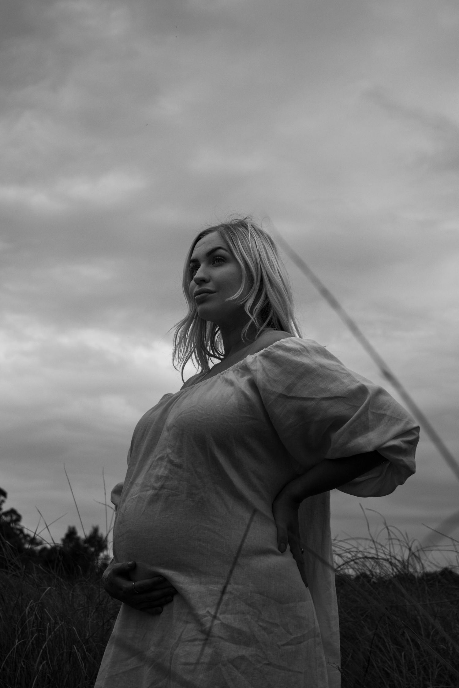 Dramatic grayscale photo series of person turning and moving through windswept field under overcast sky.