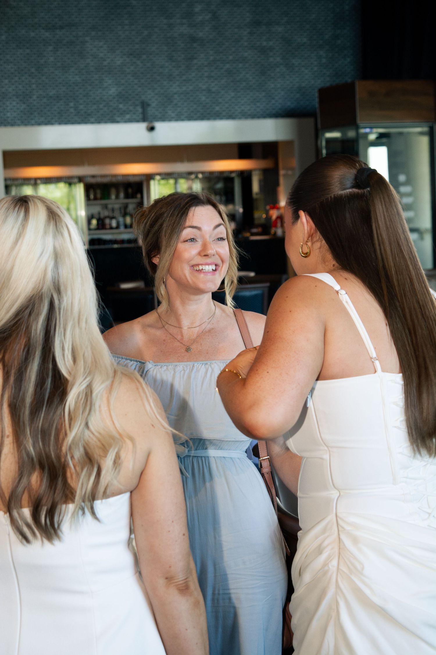Women in light-colored dresses sharing joyful moments together.