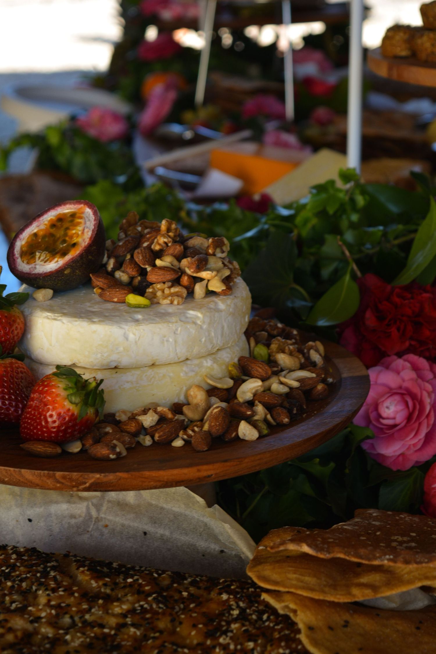 Baked brie cheese garnished with nuts and strawberries on wooden board.