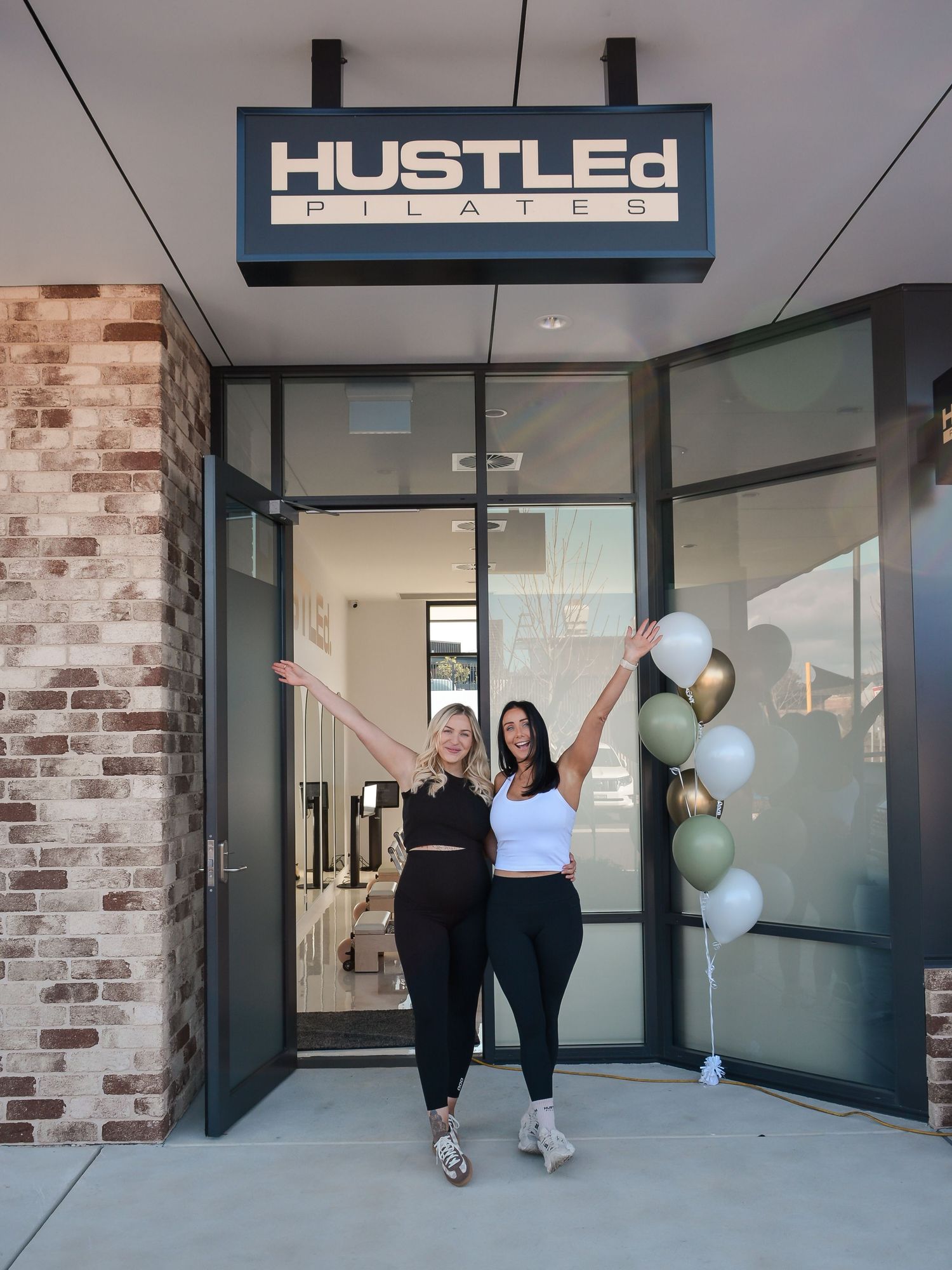 Exterior view of a retail storefront with Hustler signage and exposed brick walls.