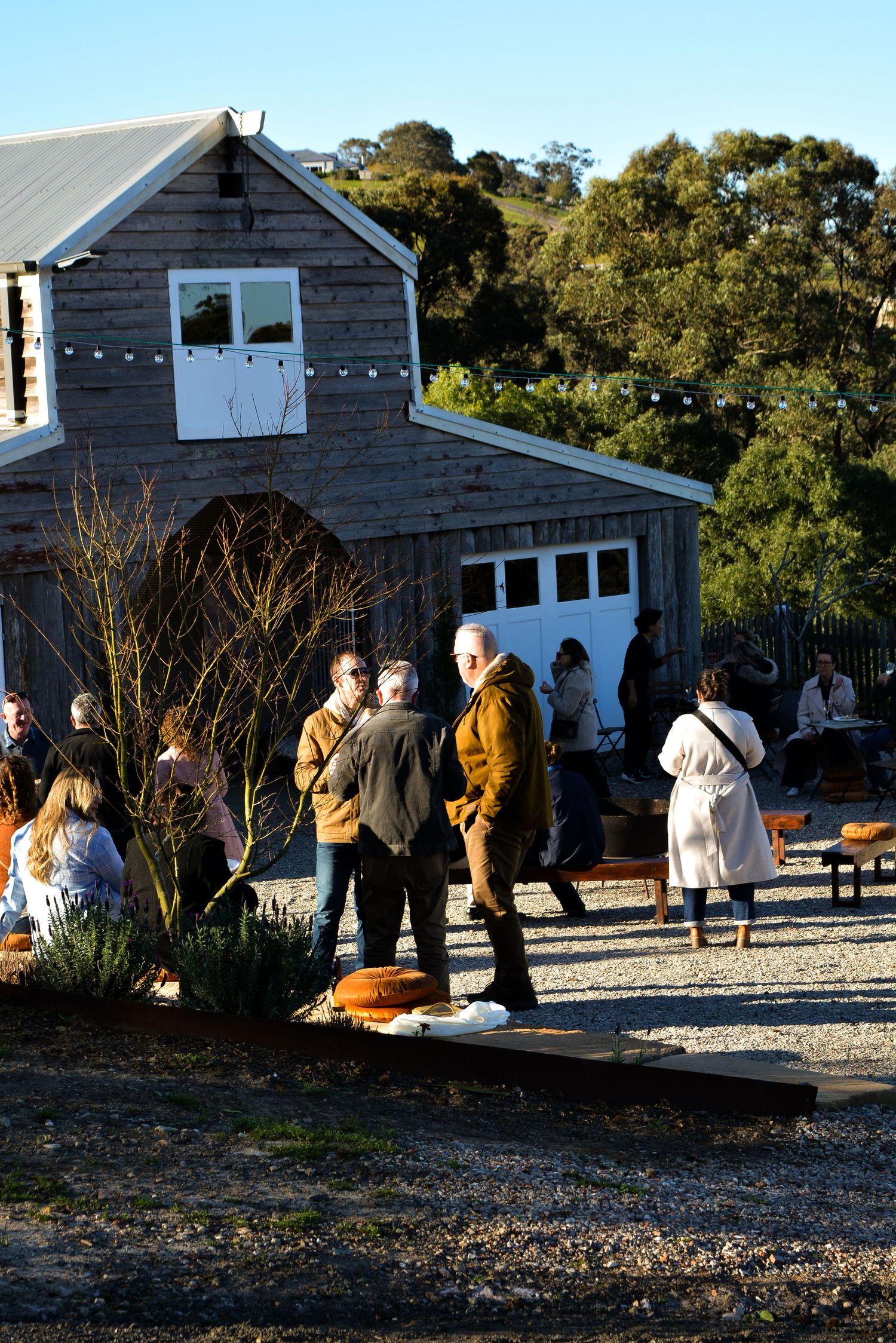 Group of people gathered outside a weathered barn-style building at dusk.
