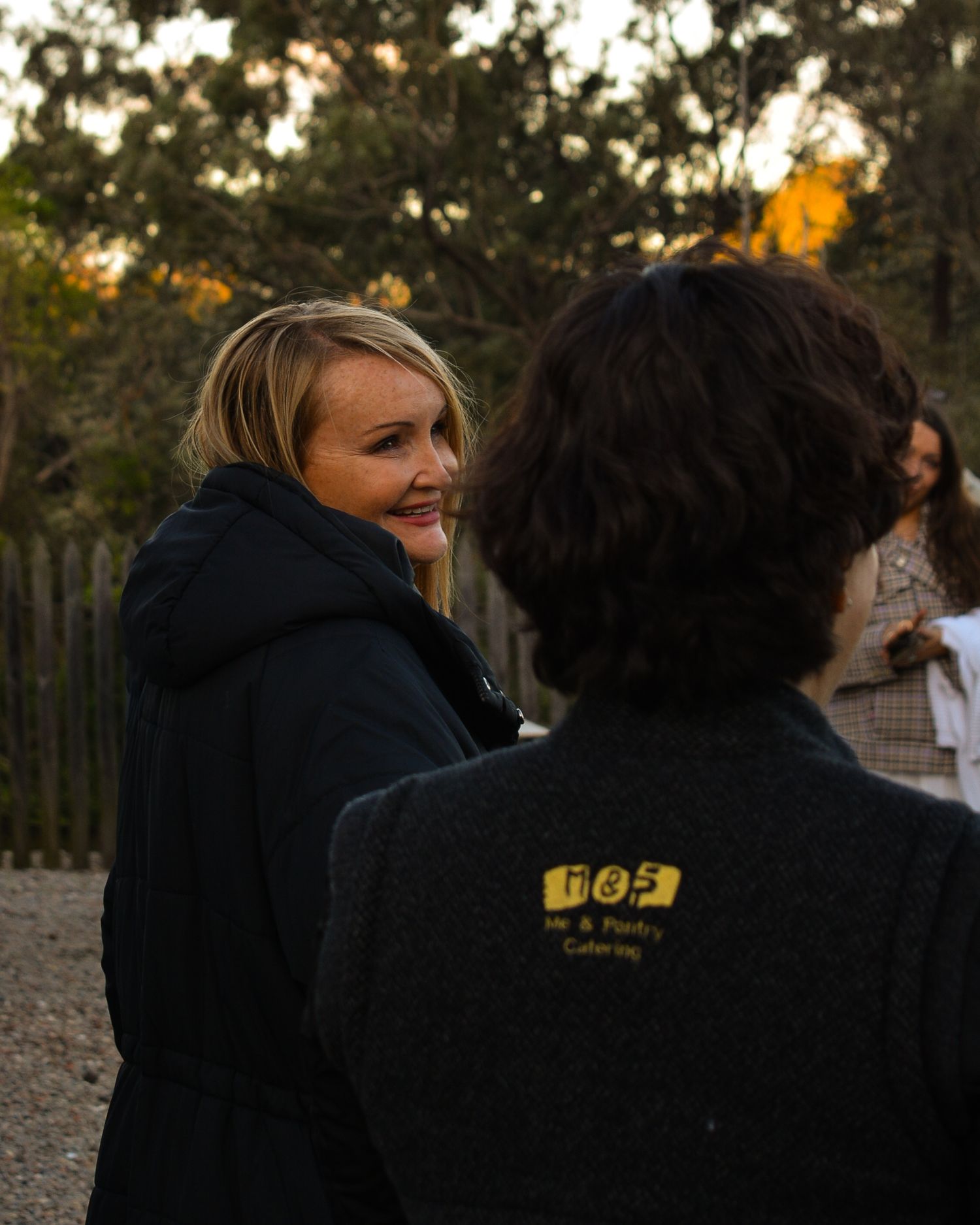 Group wearing black jackets gathered outdoors at dusk.
