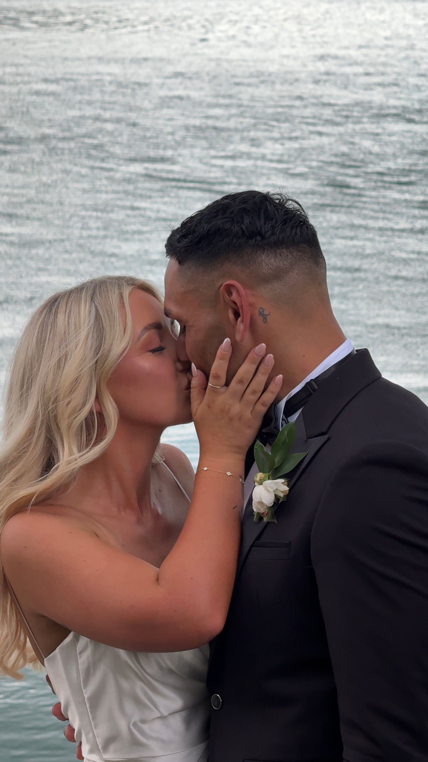 A romantic sequence of a couple sharing intimate moments by the ocean during a wedding ceremony.