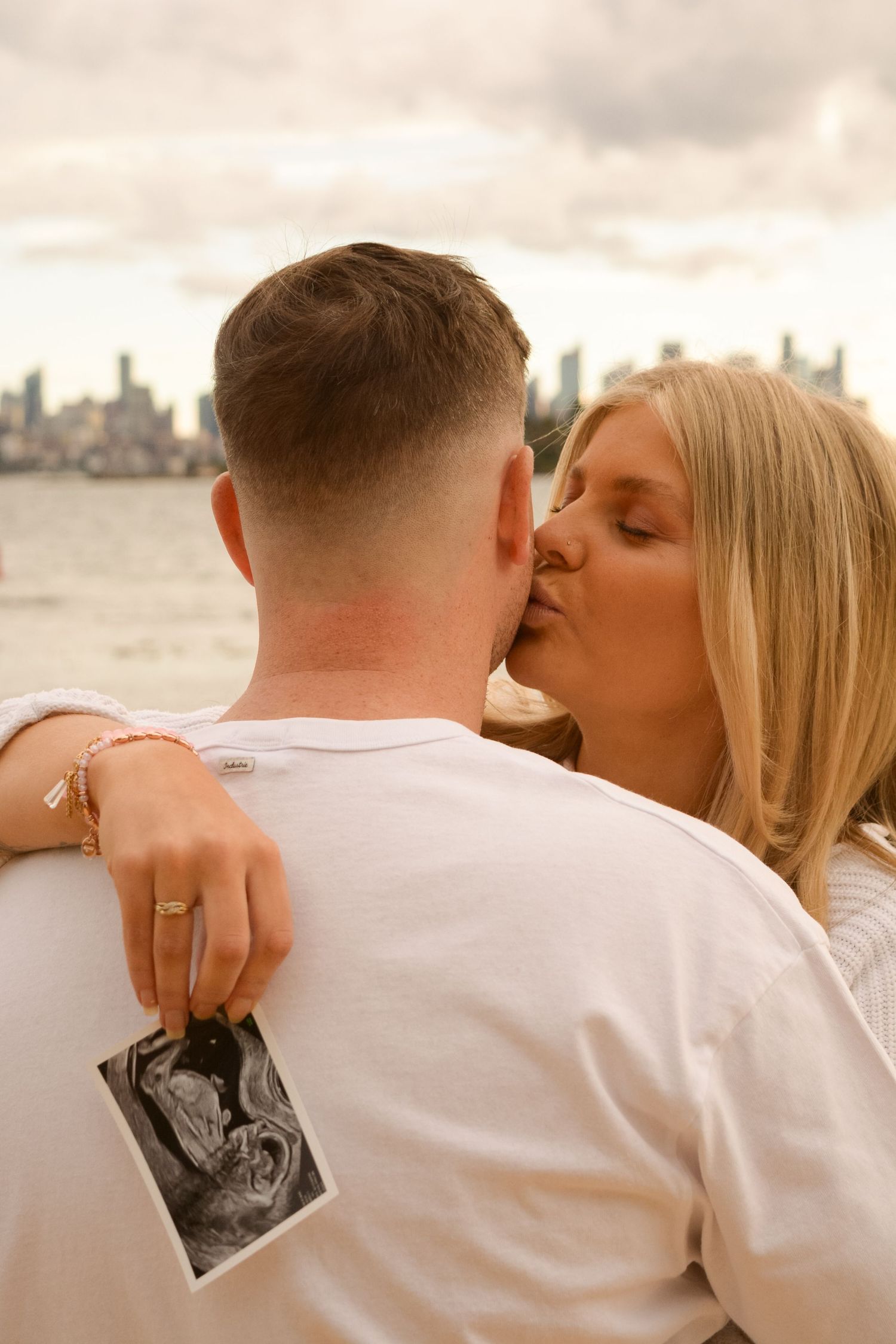 A romantic moment captured between two people holding a photograph at sunset.