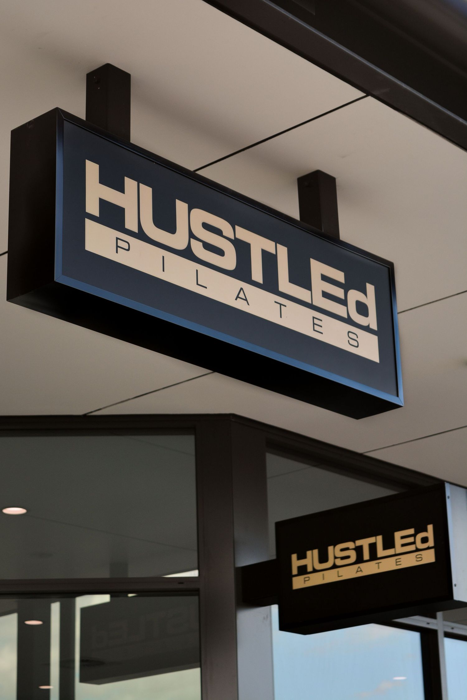 Modern black signage for 'HUSTLED' business displayed on a white interior wall.