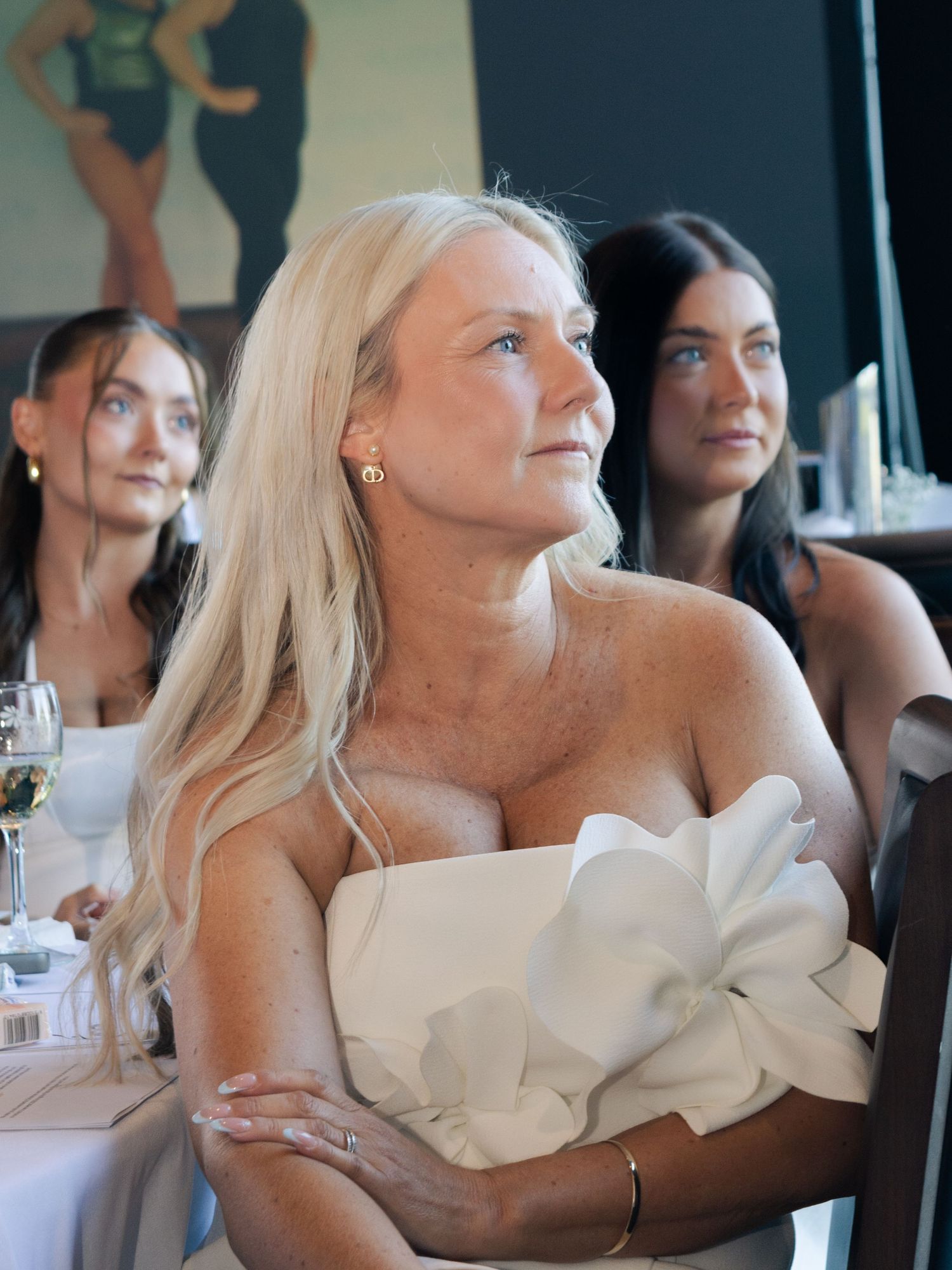 A woman in a white off-shoulder dress sits at an elegant table setting.