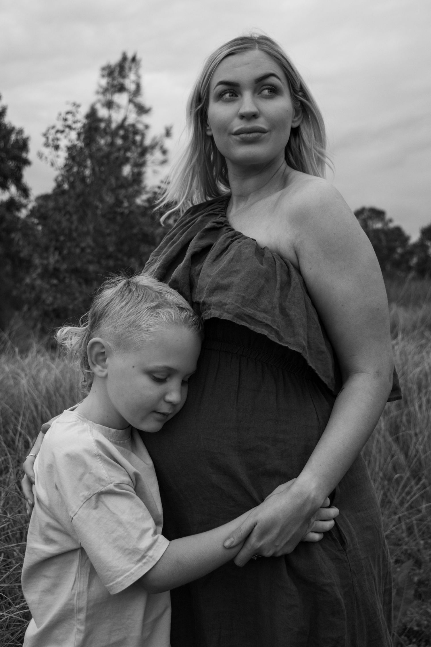 A series of black and white photos showing tender moments between a parent and child in a grassy field.