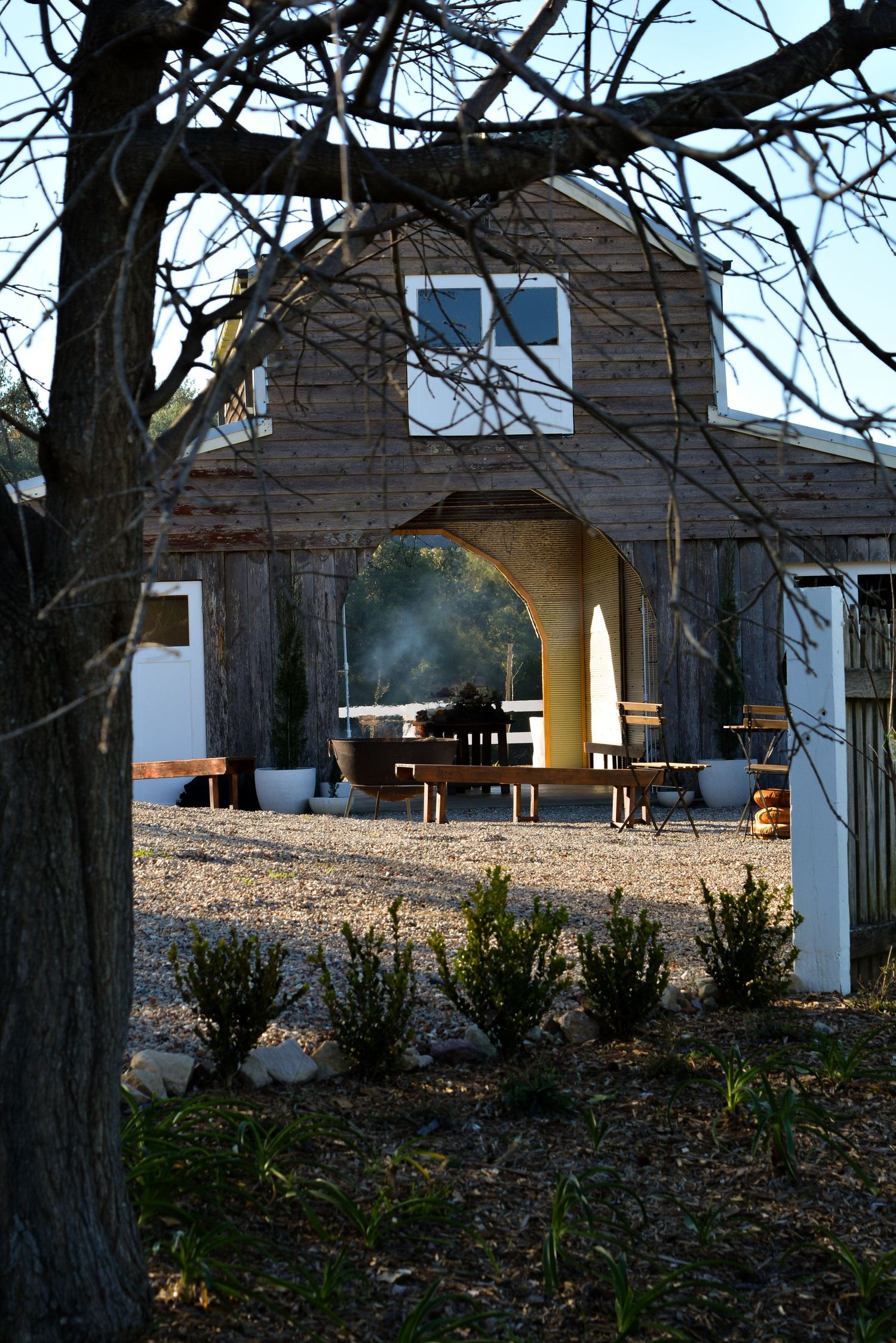 White pavilion with picnic tables visible through bare winter trees.