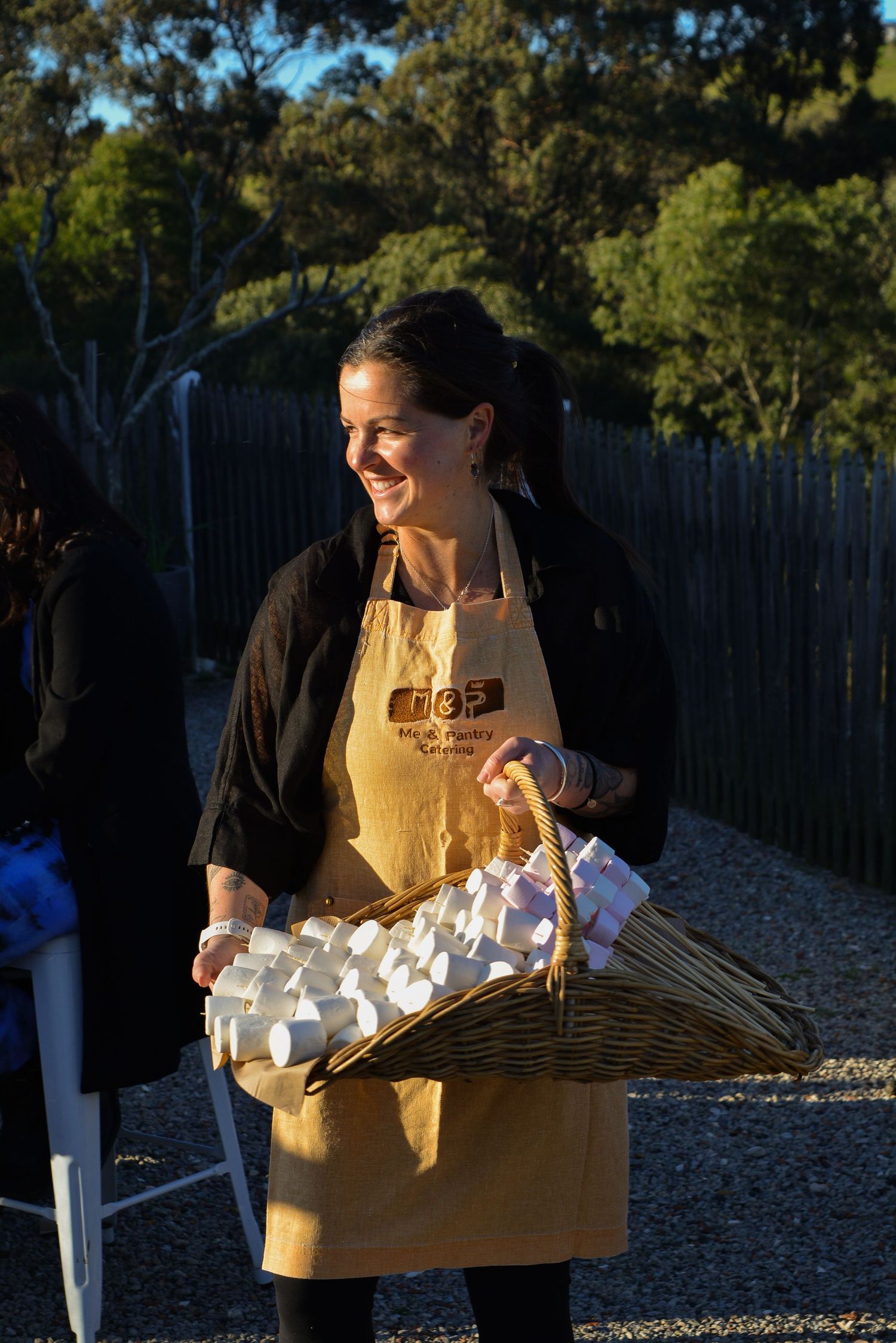 Person in yellow apron carrying a large woven basket filled with eggs outdoors.