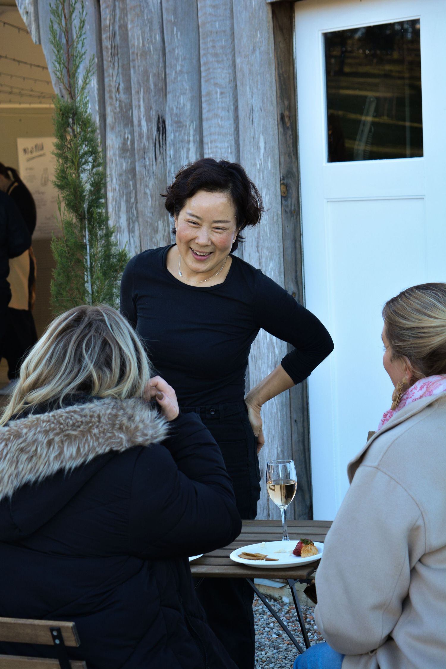 People enjoying a casual outdoor gathering near a rustic building.