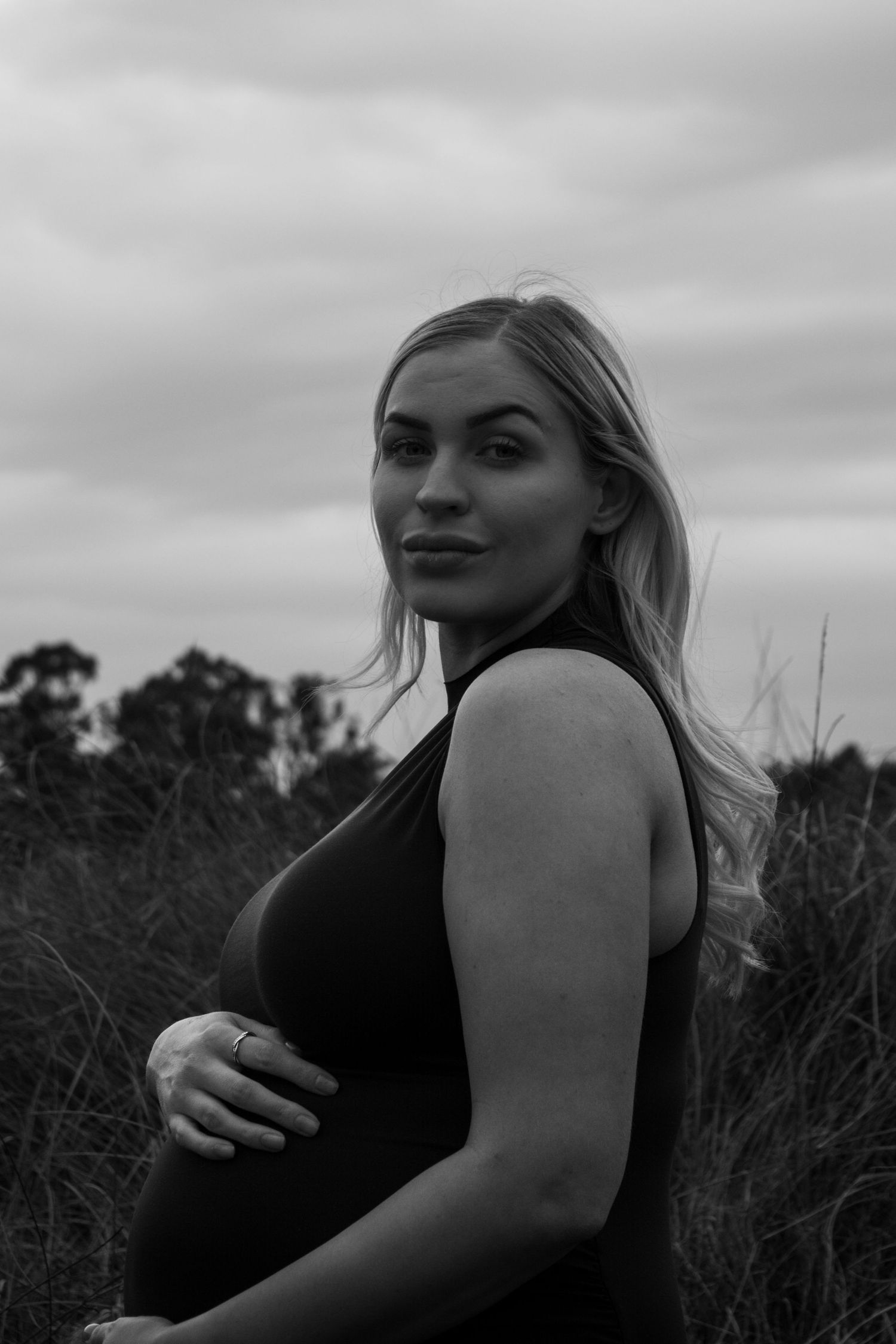 A black and white photo series shows a person posing thoughtfully in tall grass against a cloudy sky.
