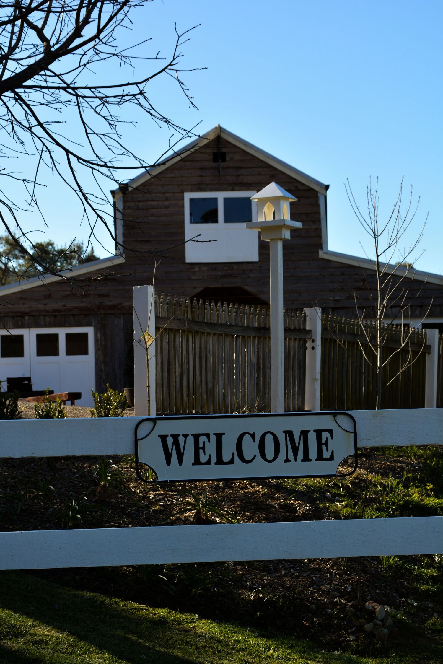 Rustic wooden buildings with white trim and welcome sign in front.