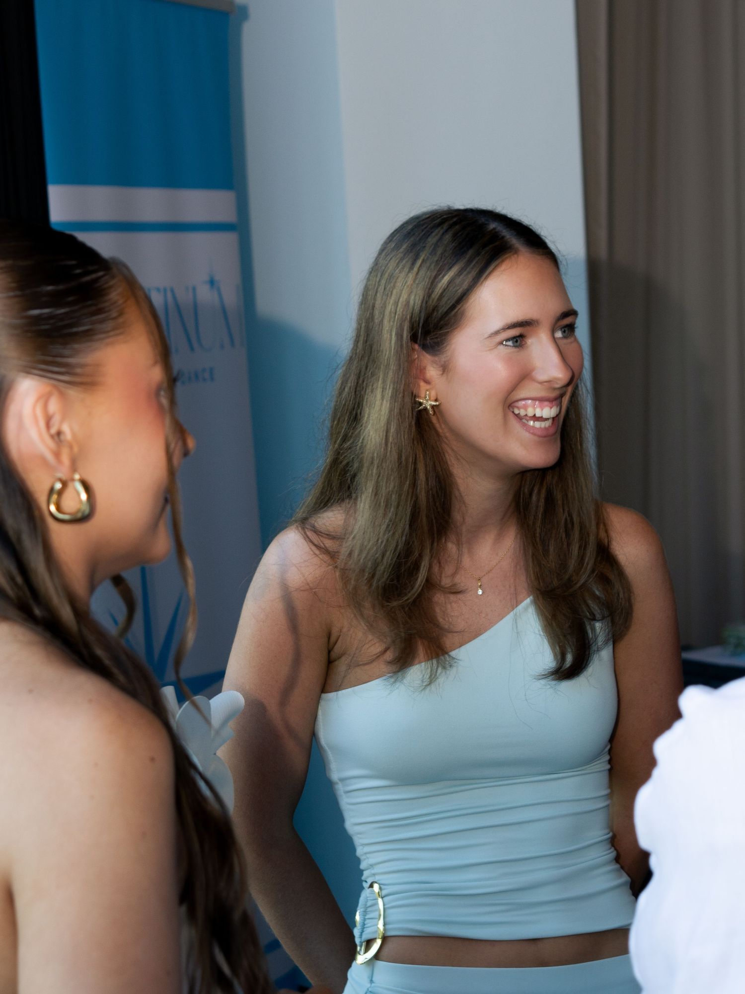 Friends in casual summer attire laughing together indoors.