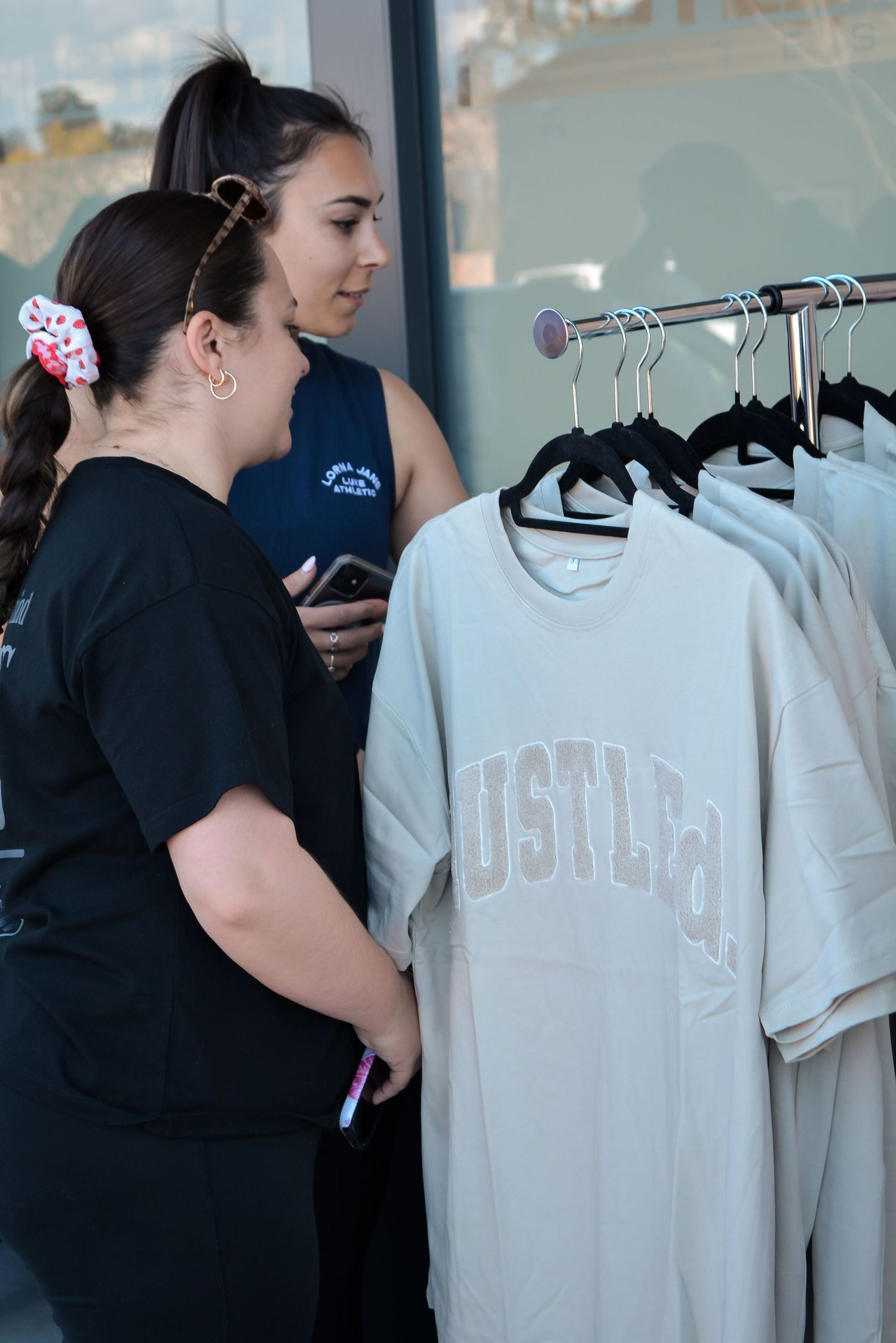 Clothing rack displaying light-colored t-shirts with USMLA branding in a retail store setting.