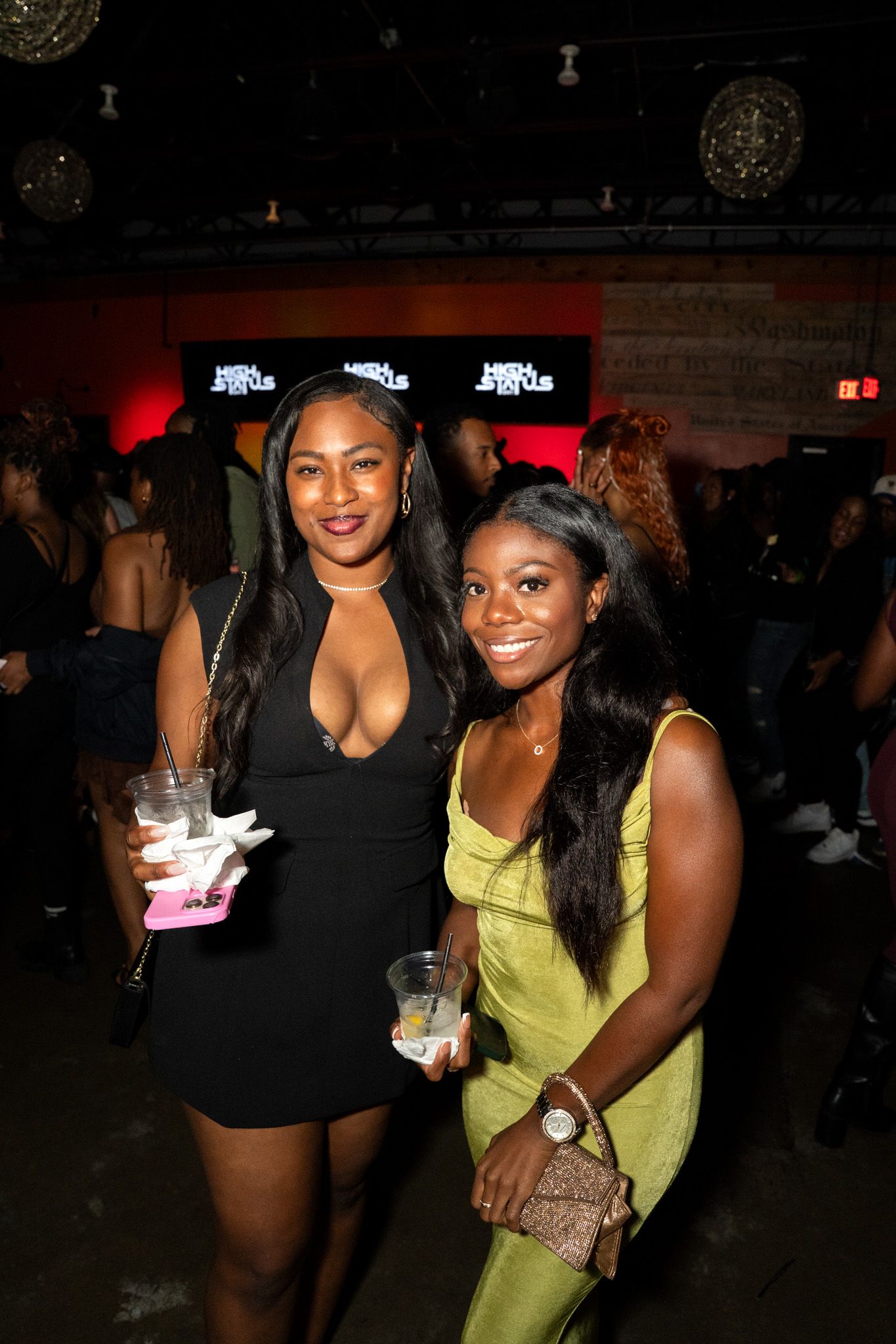 Two friends enjoying a night out at a club with drinks and smiles.
