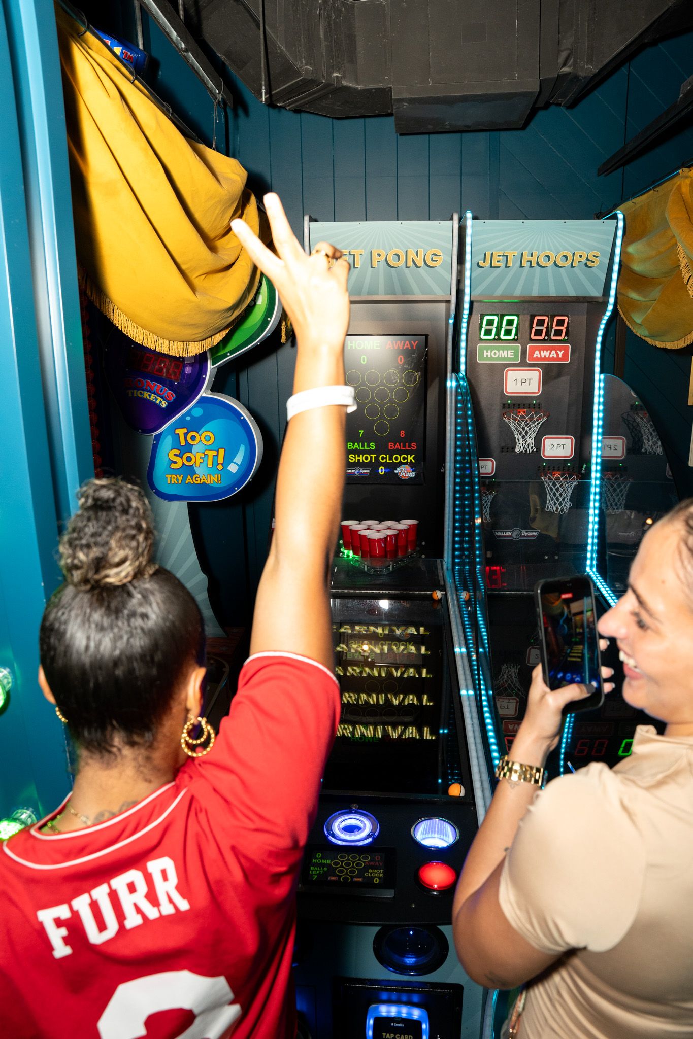 Players competing at basketball arcade games with digital scoreboards visible.