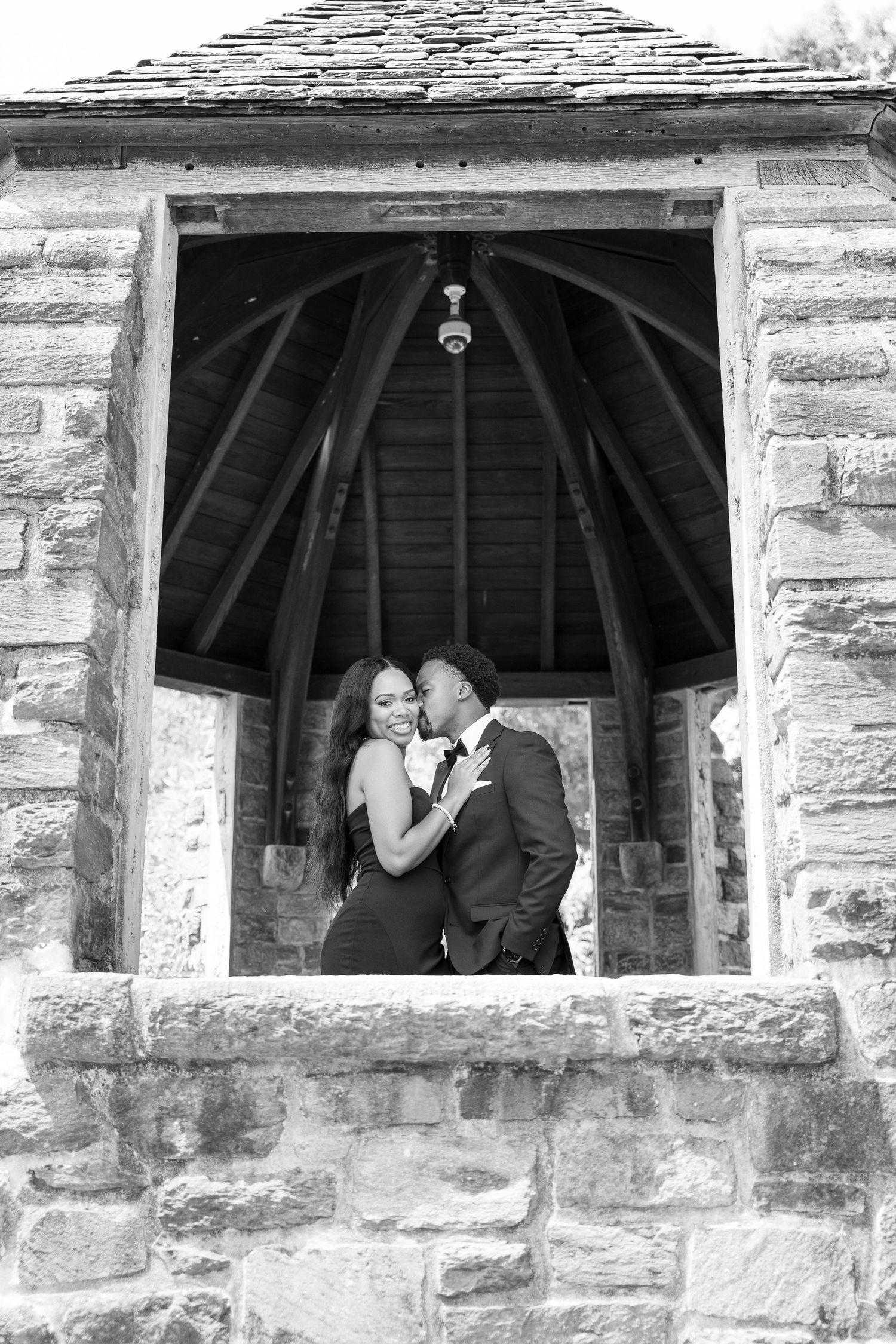 Black and white wedding portraits through stone archway windows.