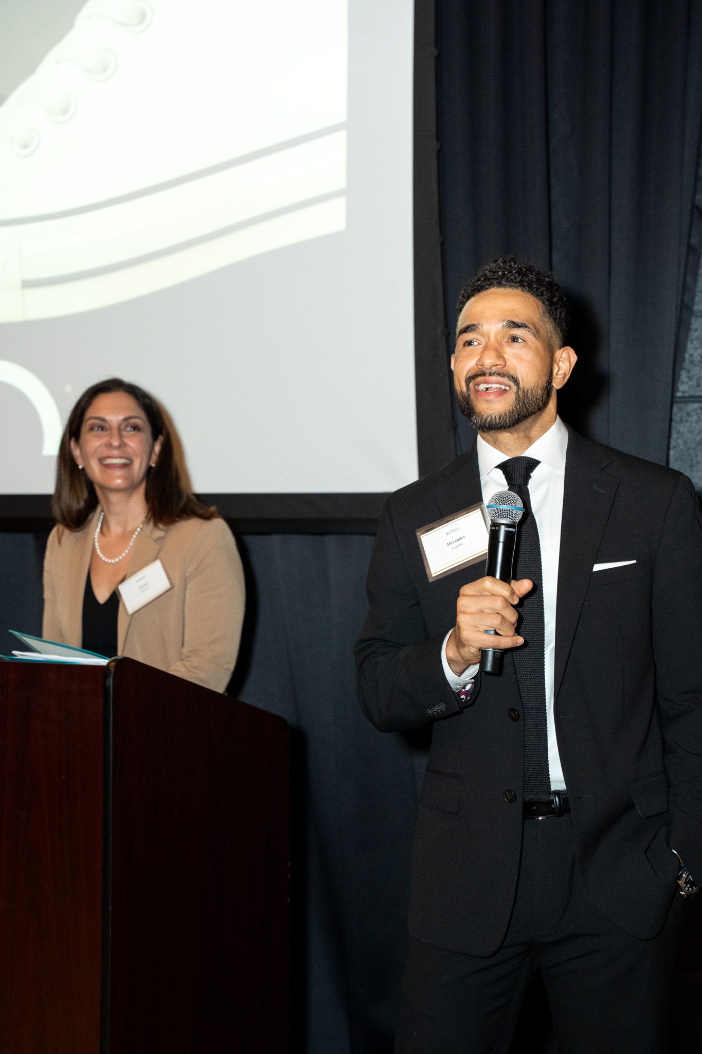 A series of four candid photos showing speakers presenting and laughing on stage at a professional event.
