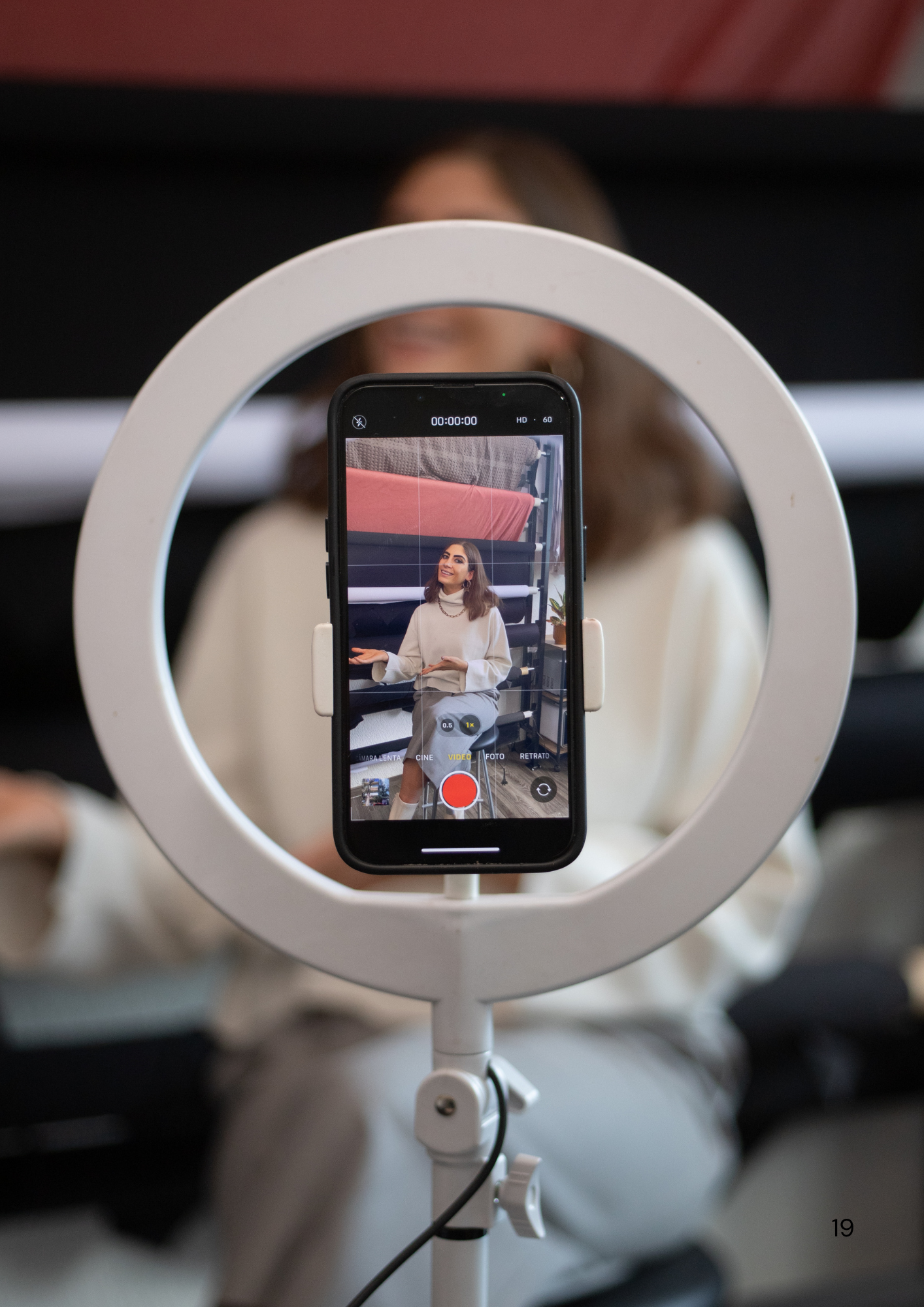 Circular ring light displaying mobile device during video production setup.