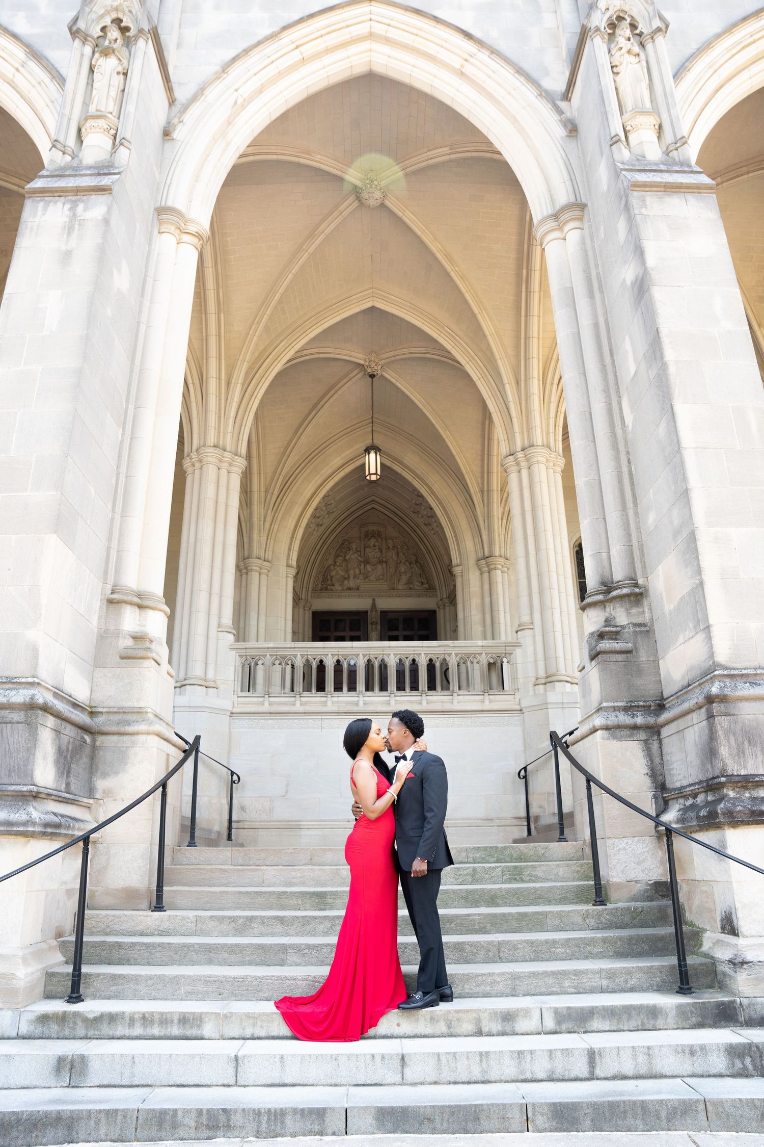 Couple shares romantic moment on stone steps of Gothic church entrance.
