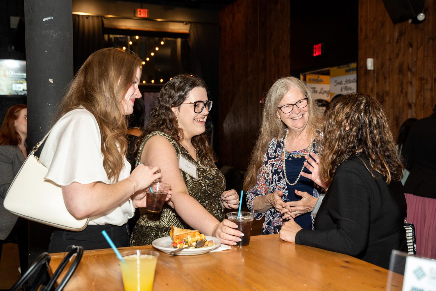 Group of friends sharing drinks and conversation at restaurant table.