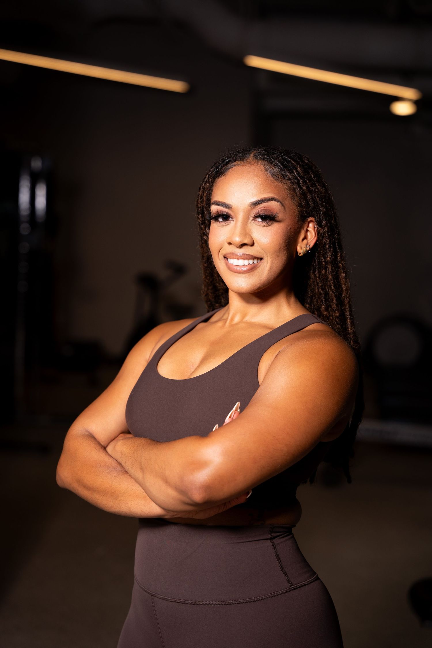 Confident pose in athletic wear during fitness photoshoot with dramatic lighting.