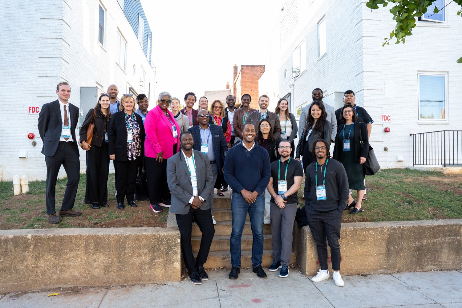 Large group of professionals gathered outside a white building for a group photo.
