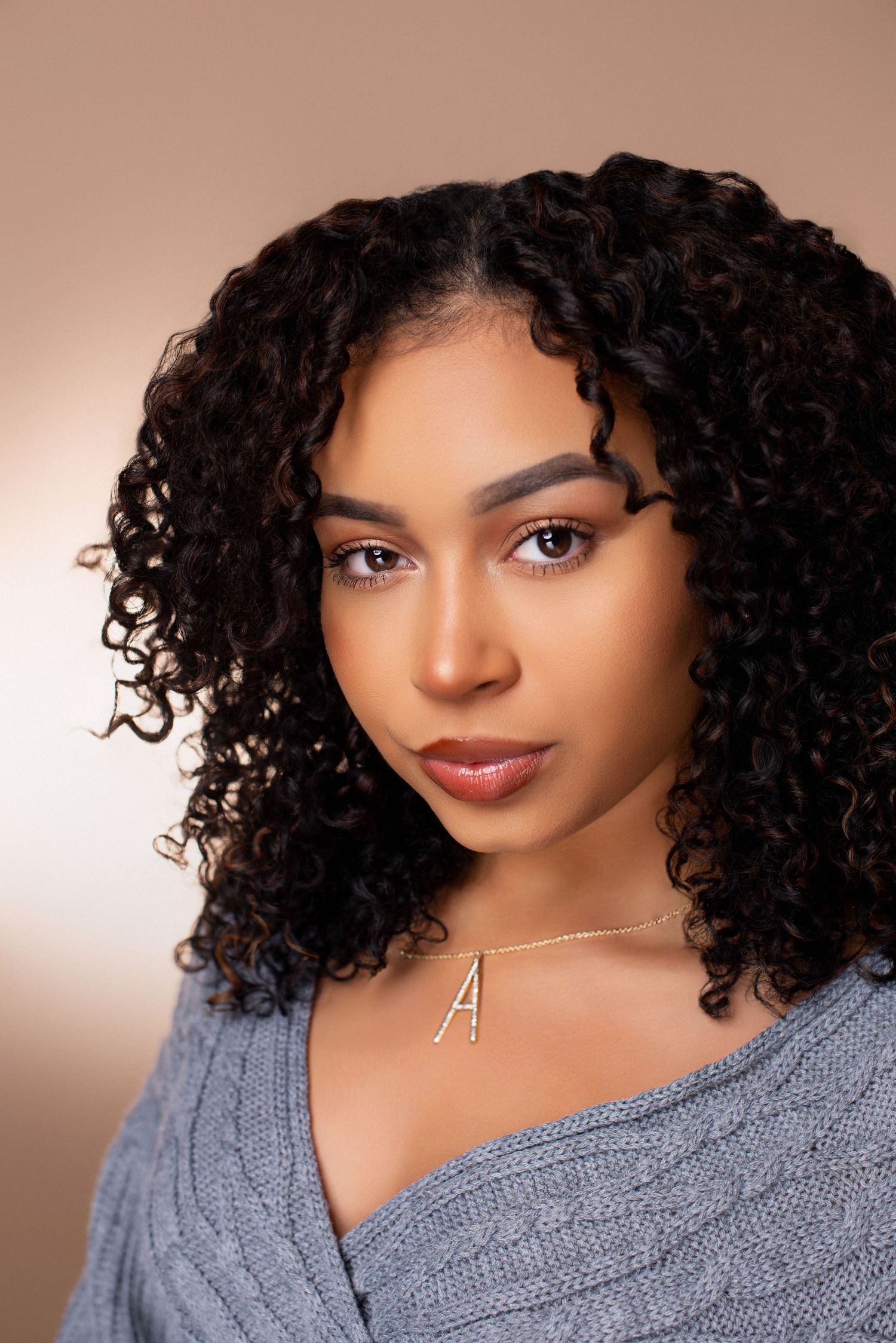 Warm-toned portrait series featuring cozy sweater and natural curly hair styling.