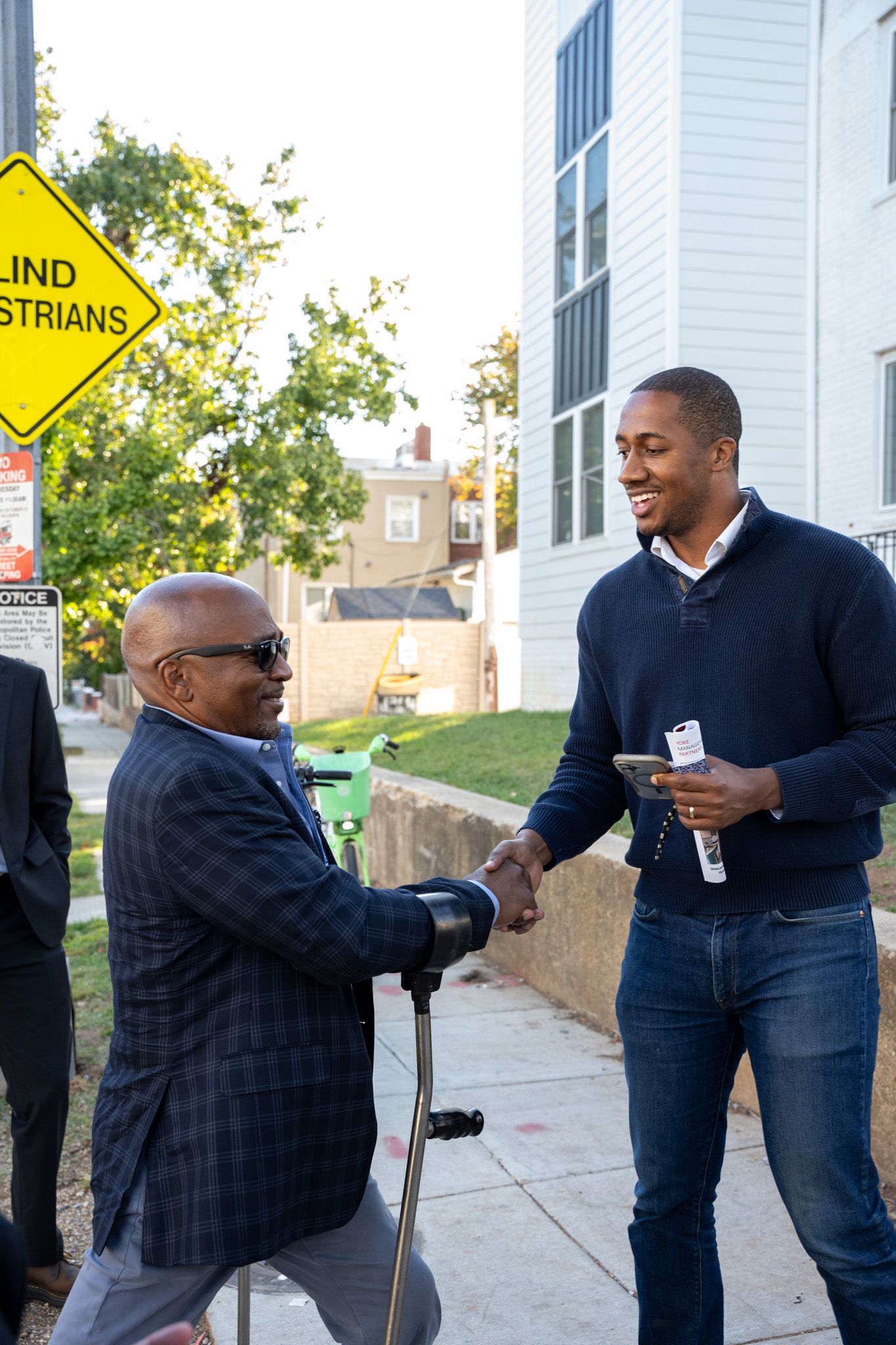 Colleagues sharing a friendly greeting and handshake outside an office building.