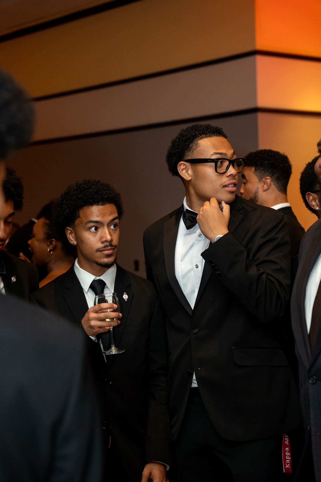 Young guests in formal black tie attire socializing at an elegant evening event.