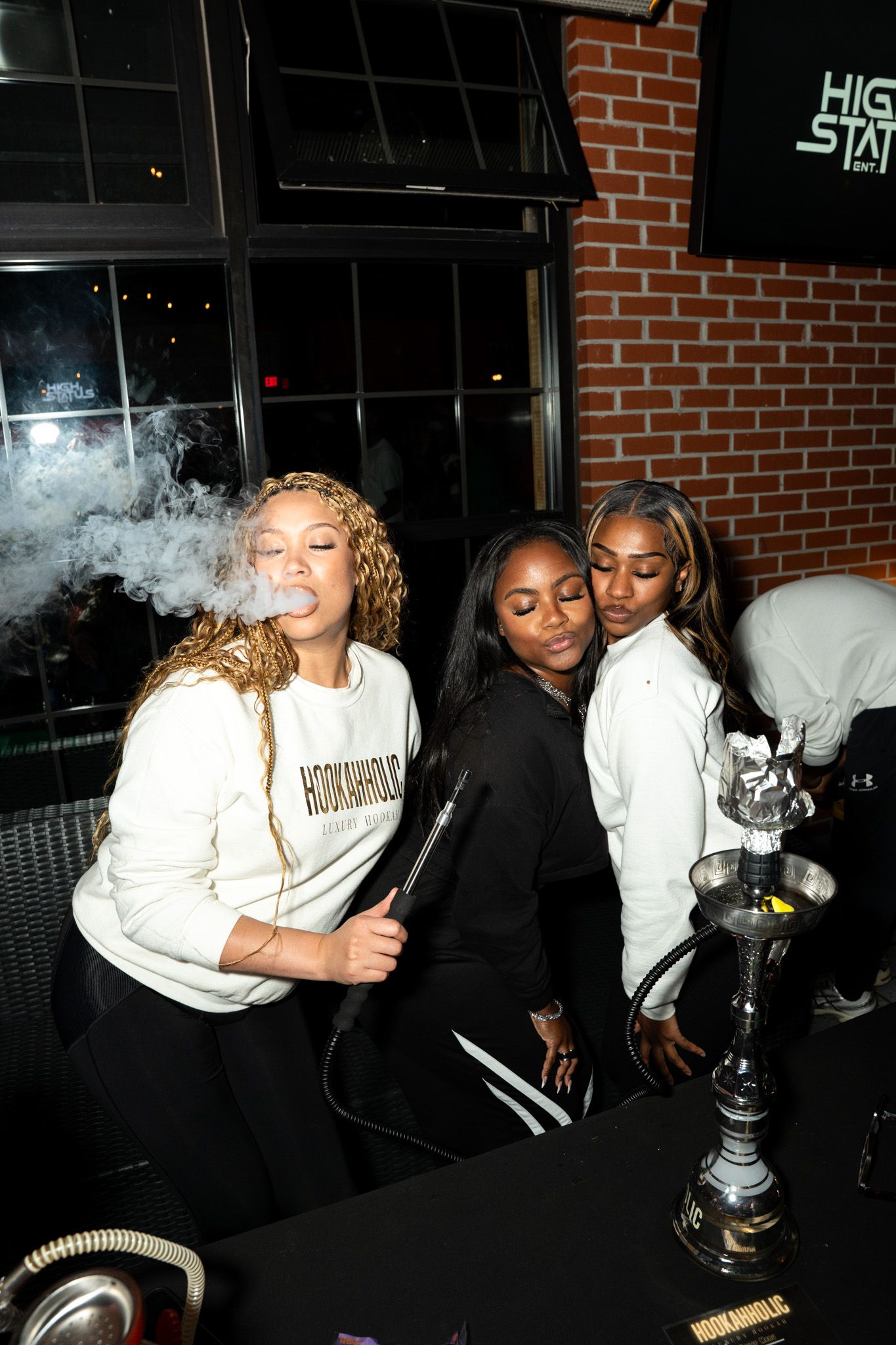 Friends gathered around a hookah at a brick-walled lounge.