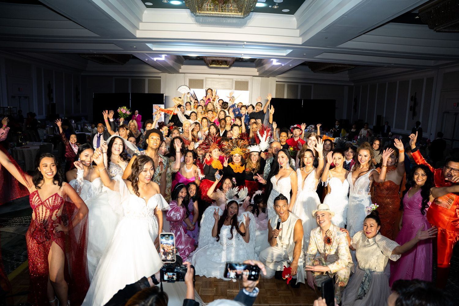 Attendees at a formal charity gala raise their hands in celebration during group photo.