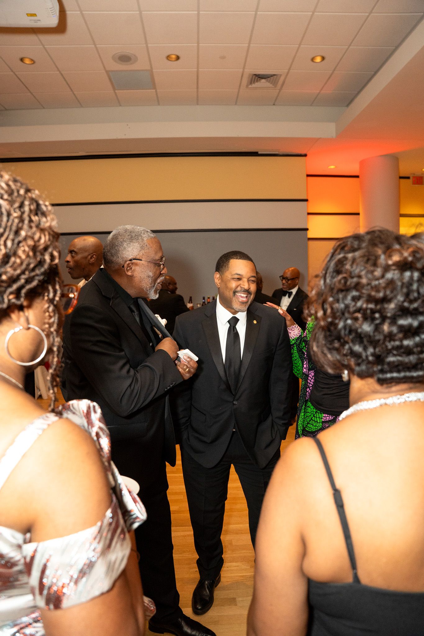 Guests mingling and socializing at a formal evening event with warm lighting.
