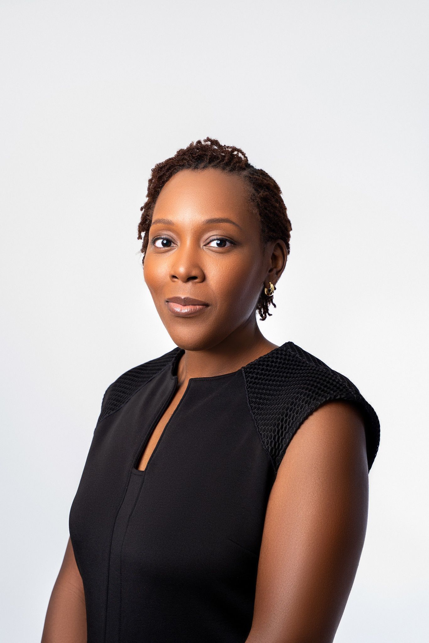 Professional studio portrait against white background featuring elegant black sleeveless top.