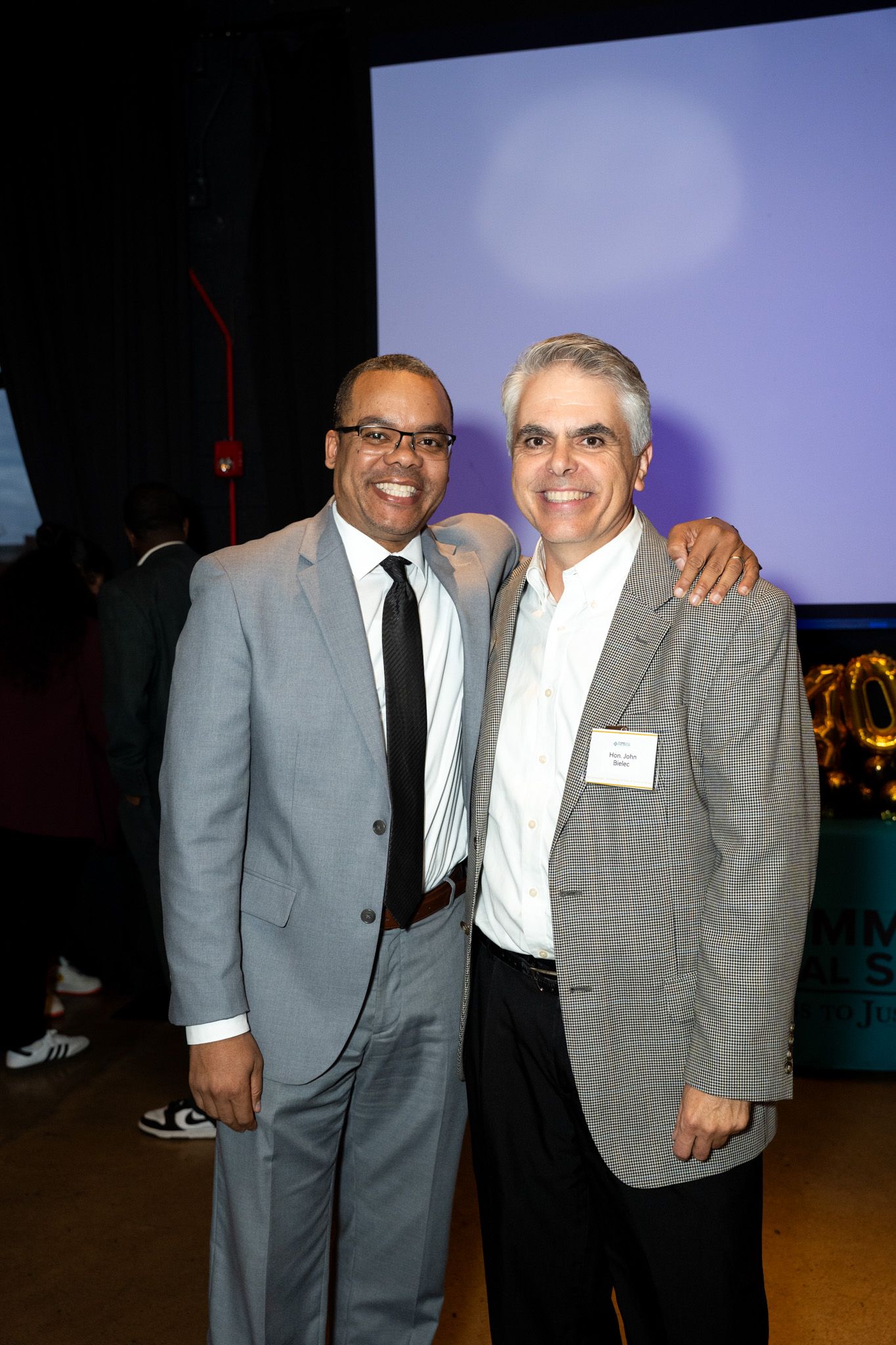 Two professionals in suits posing together at a formal business event.