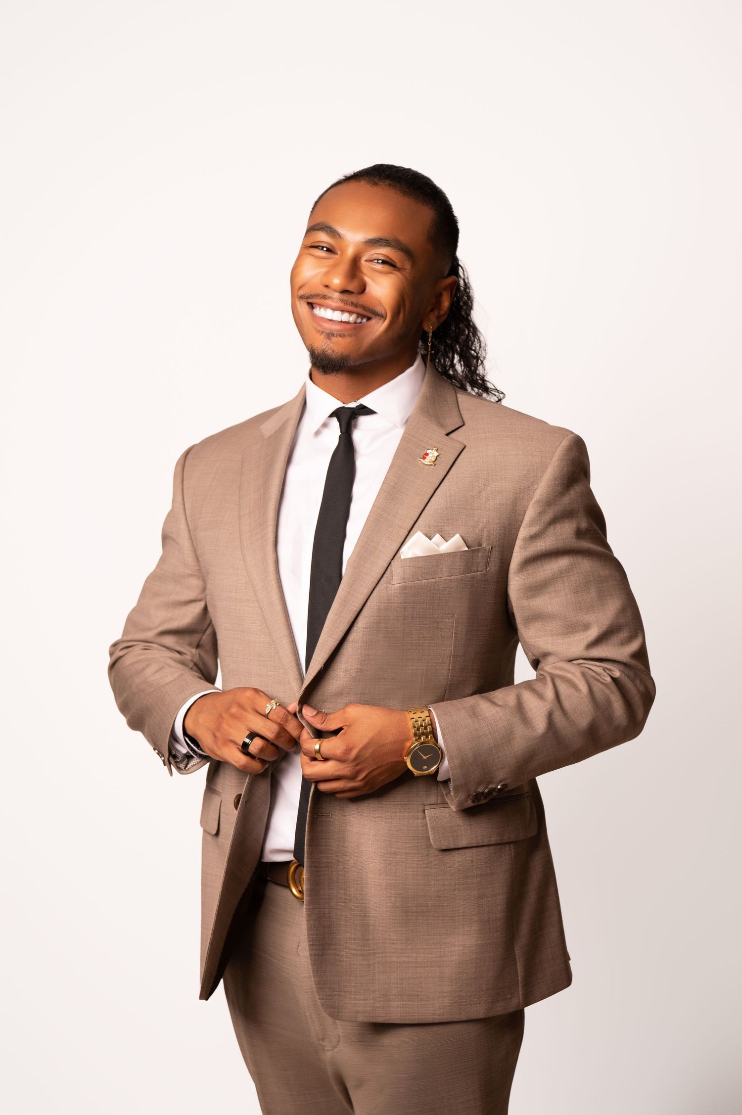 Professional portraits in tan suit and tie against white studio background.