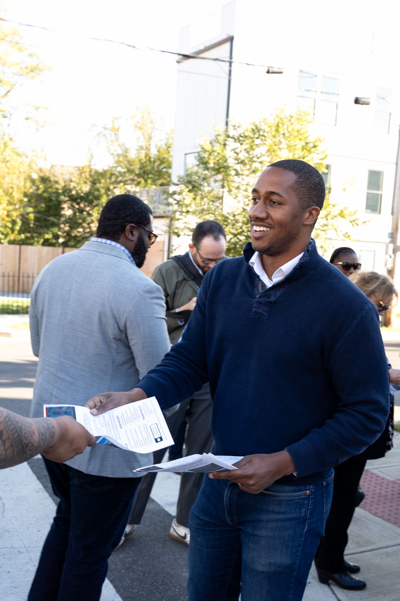 People in business attire sharing documents and conversations outdoors.