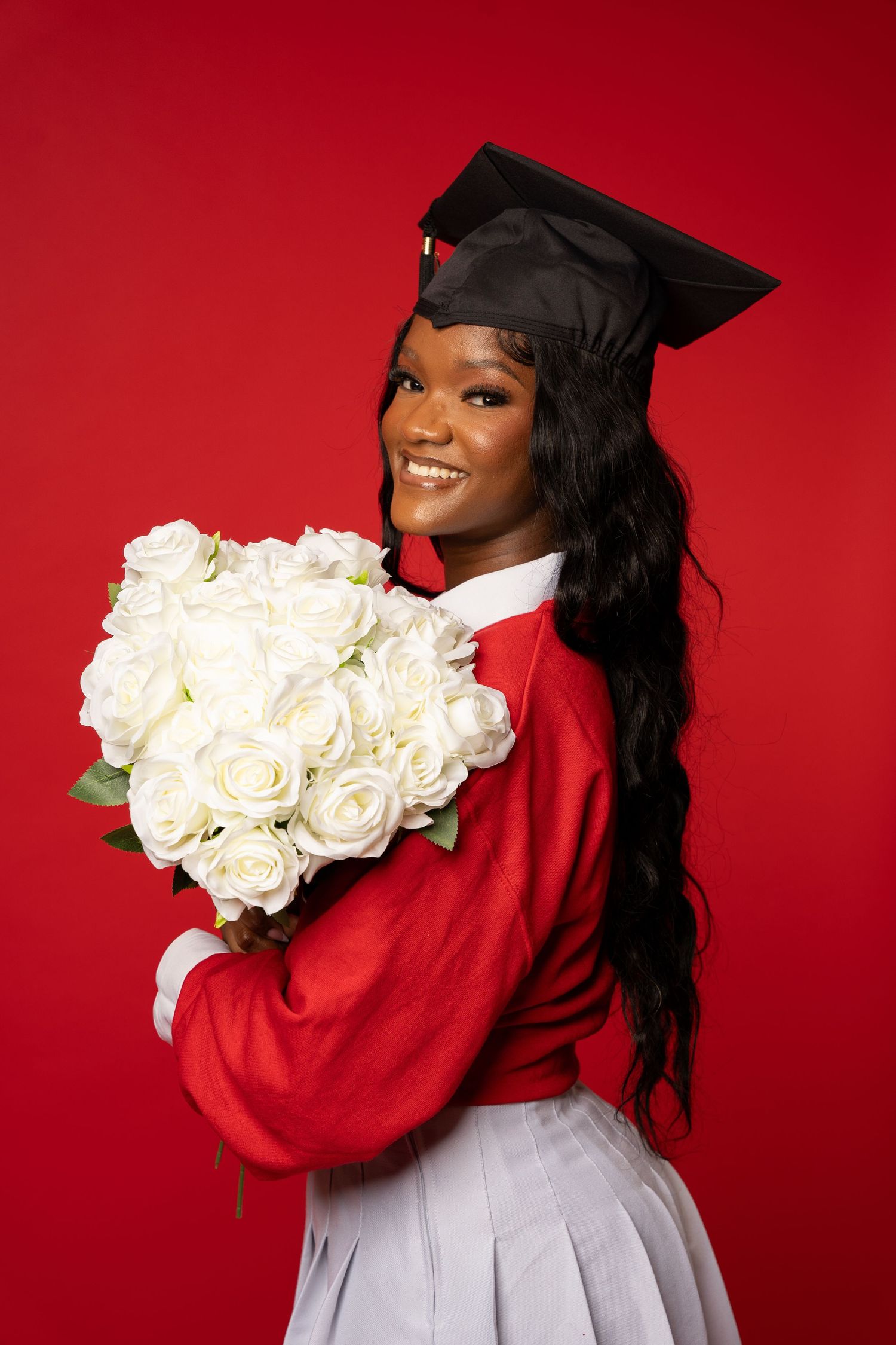 Graduation photos against a red backdrop featuring white roses and academic regalia.