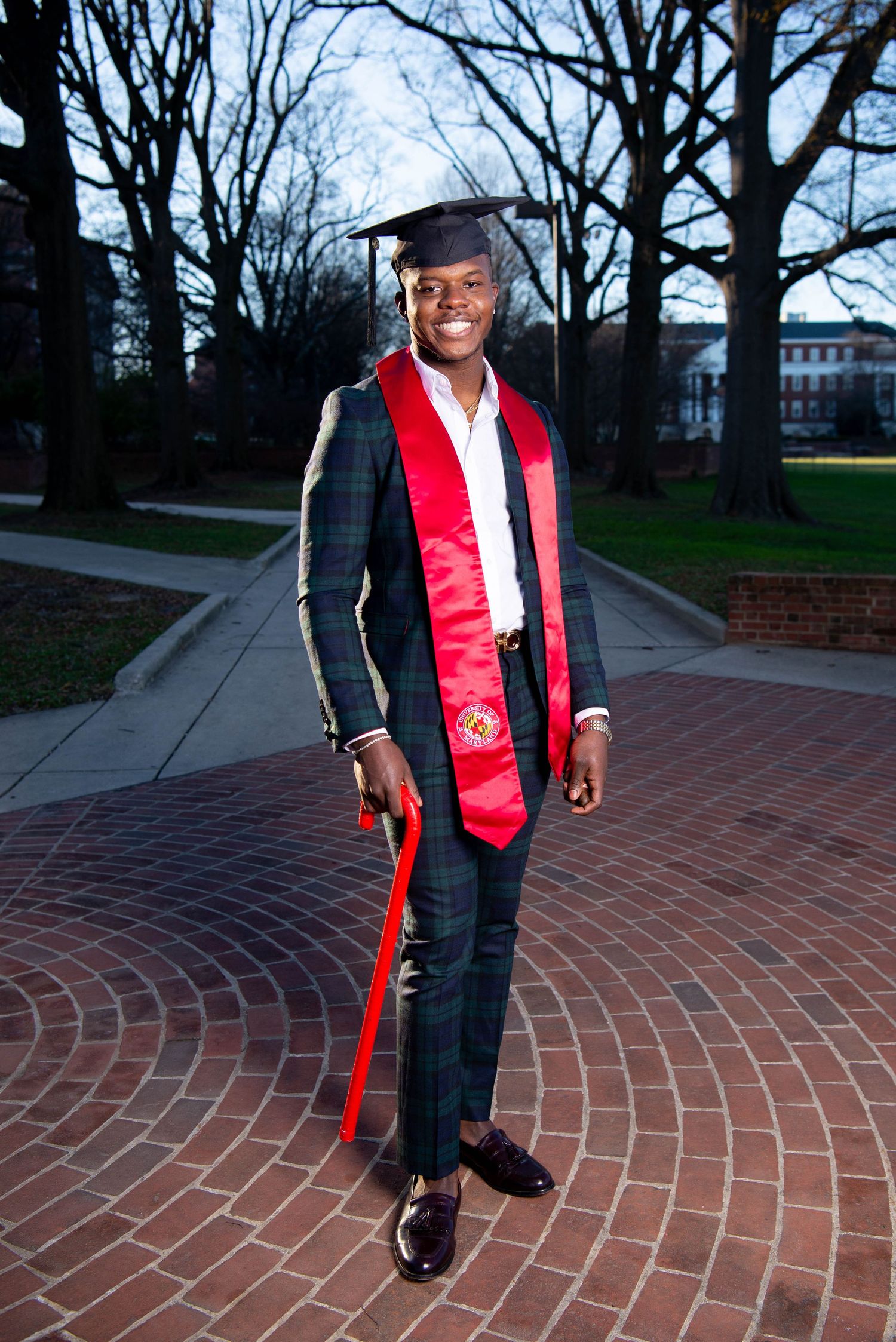 Figure wearing red vest and black attire poses on circular brick pattern walkway.