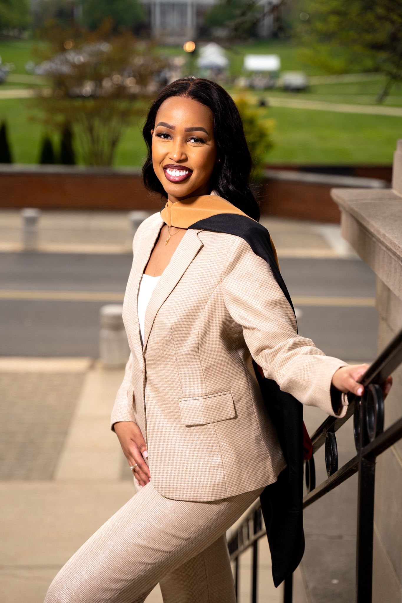 Professional portrait in beige business suit on campus steps.