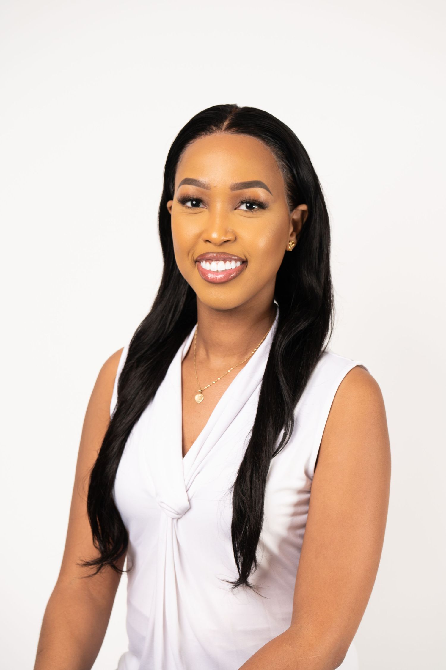 Professional portrait of someone in a white sleeveless top smiling at the camera.