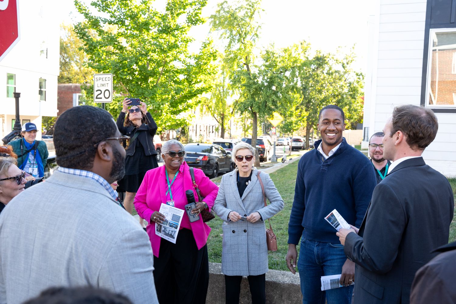 Business professionals networking at an outdoor gathering near office buildings.