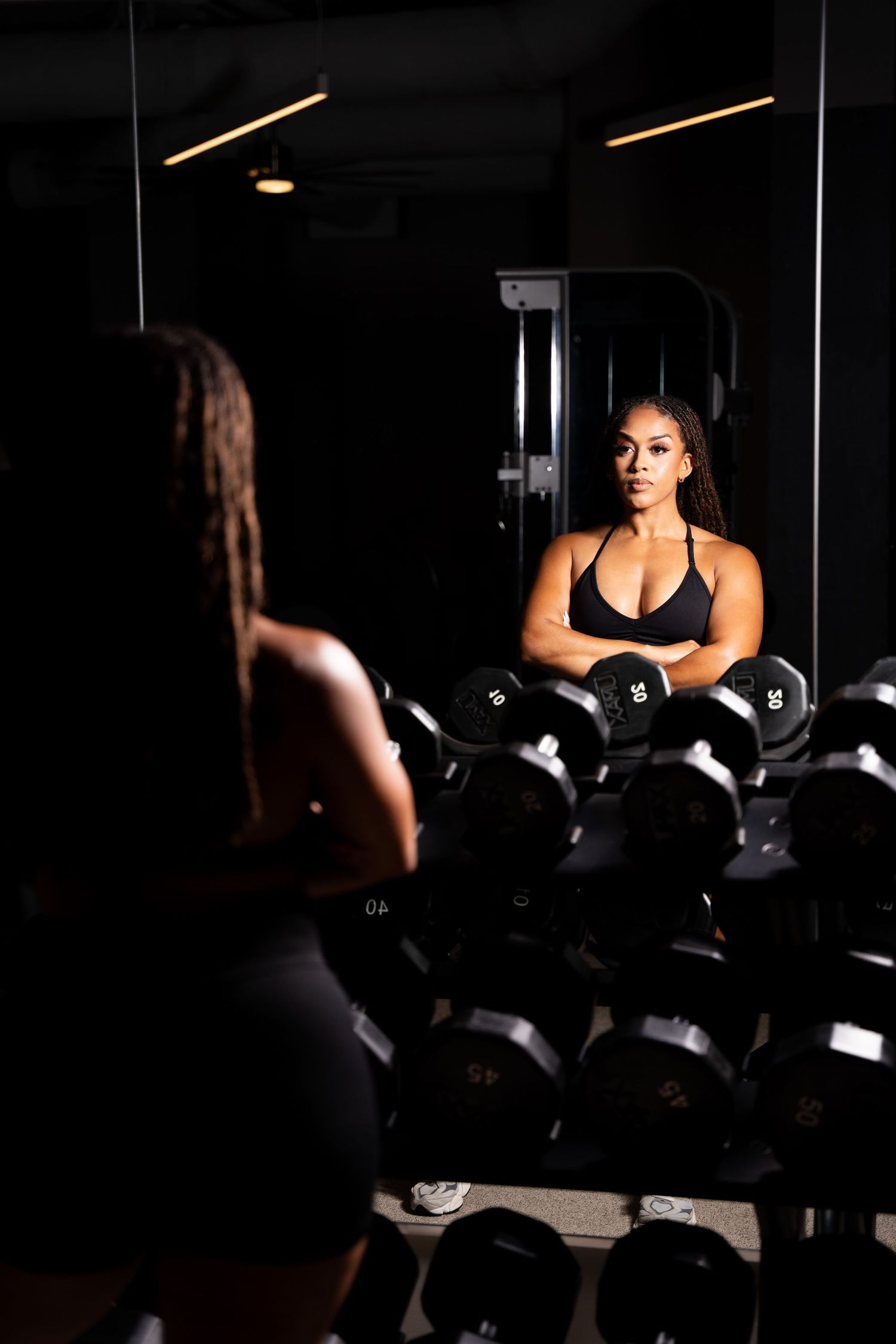 Dark moody gym photo with dumbbells rack and workout equipment.