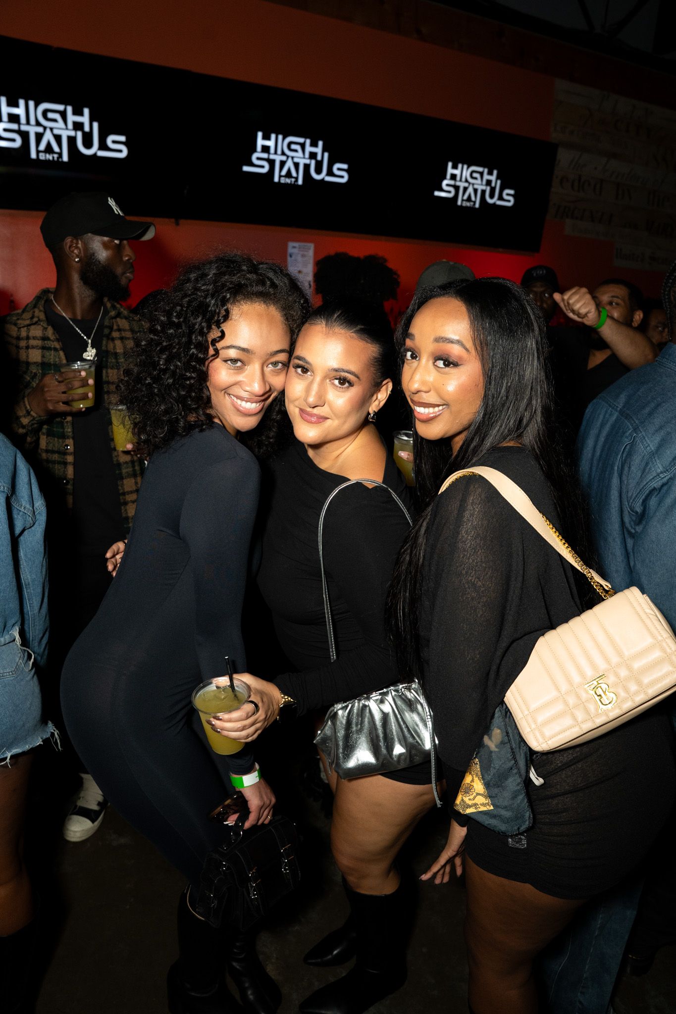 Group photo at a nightclub with 'High Status' signage visible in background.