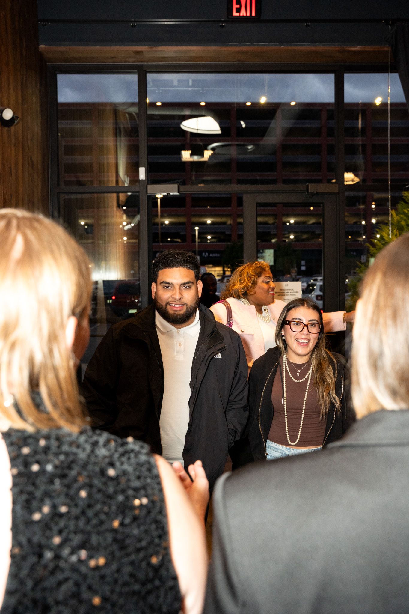Group of people mingling at an evening networking event near exit door.