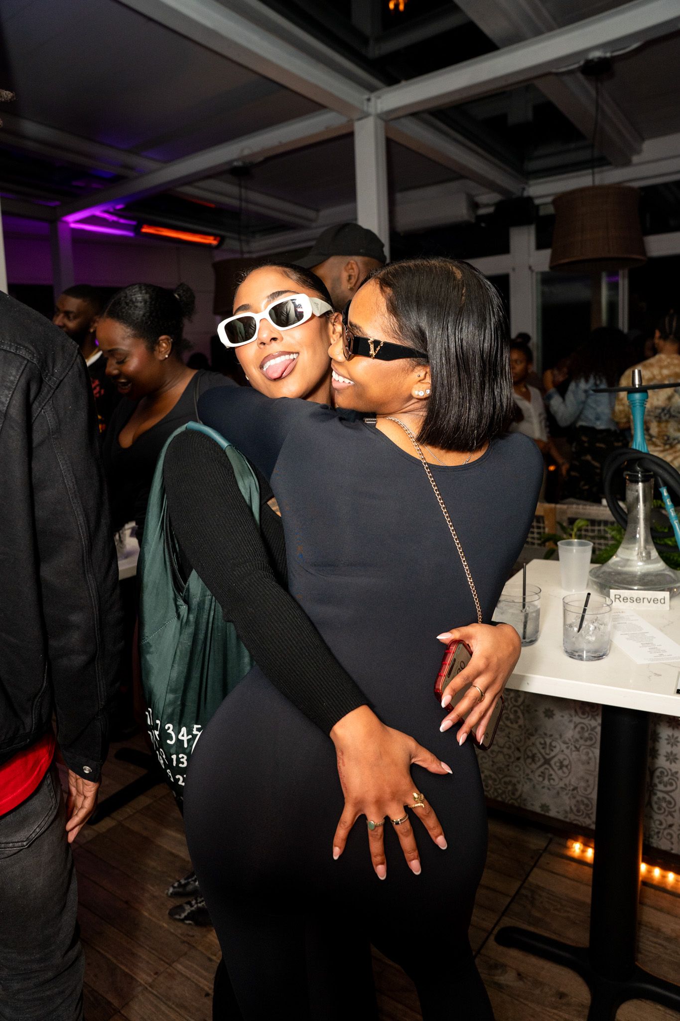 Two friends embrace while dancing at a nightclub party.