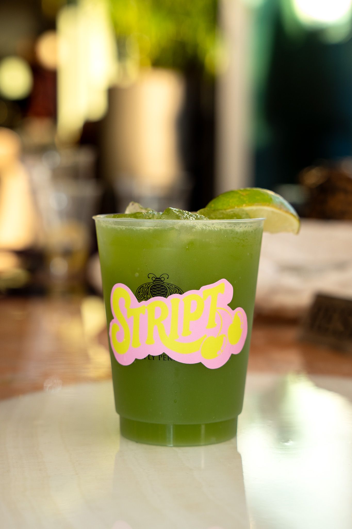 Green cocktails with branded text displayed on glasses at a bar or restaurant.